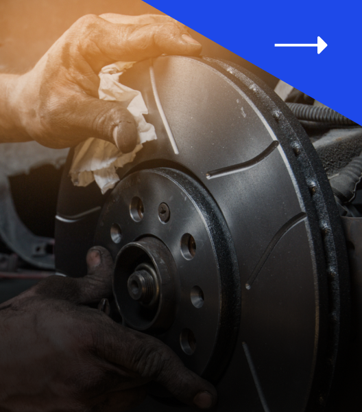 Hands cleaning a car brake rotor in a workshop, blue and orange gradient.