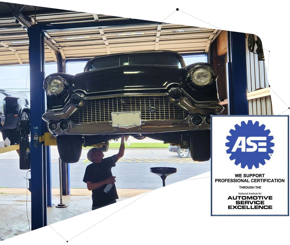 Classic black car on a lift in a garage, mechanic inspecting undercarriage. ASE certified.