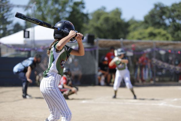 girls in green and white uniforms playing softball