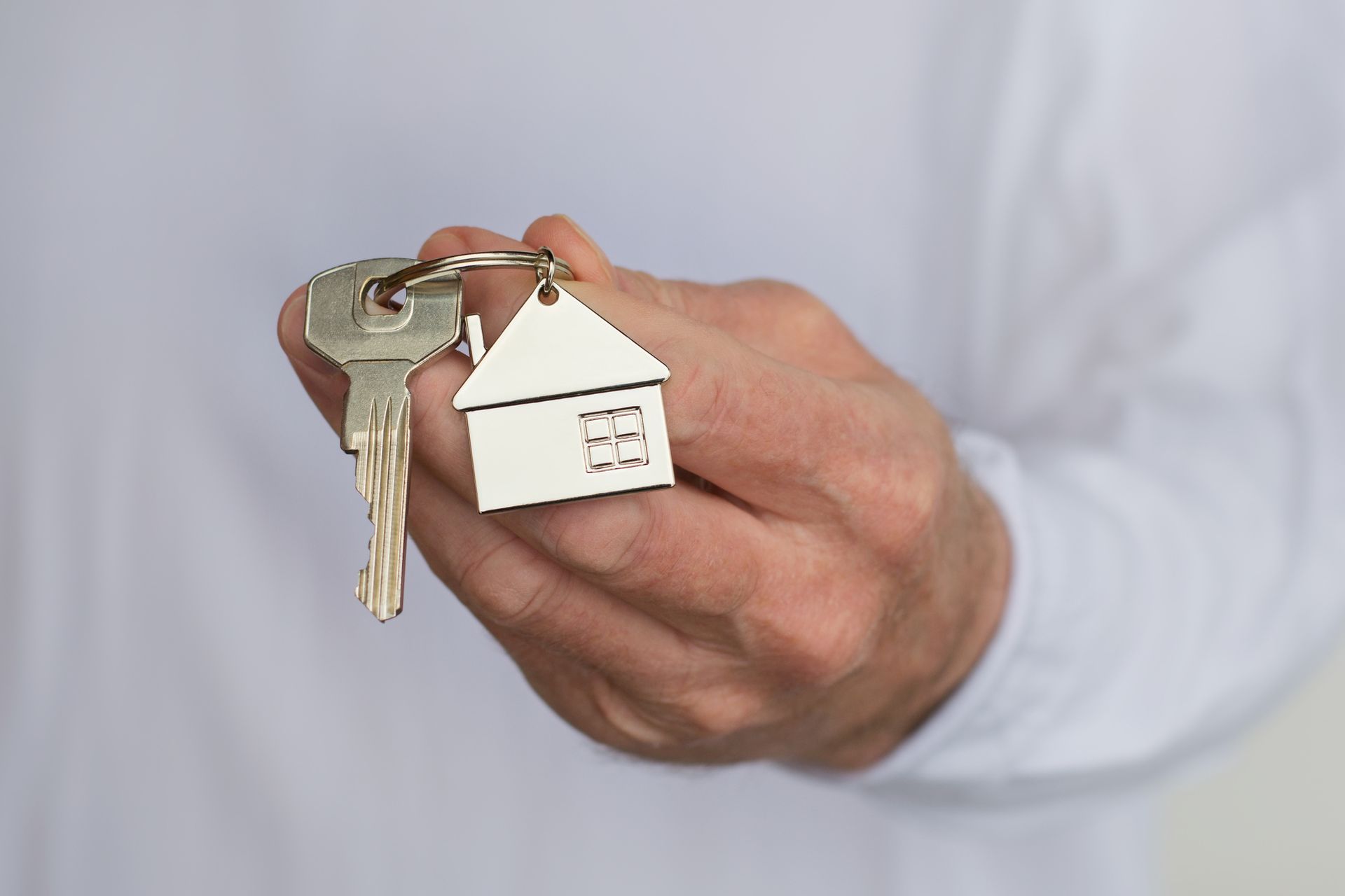 A man's hand holding a house key.