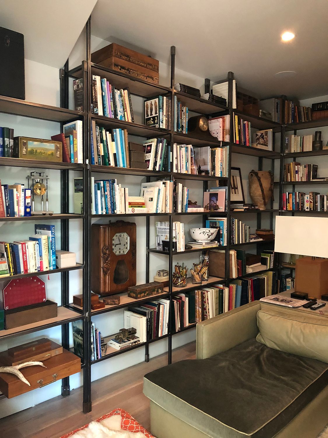Bookshelves filled with books and decorative items, a chaise lounge, and a wooden floor.
