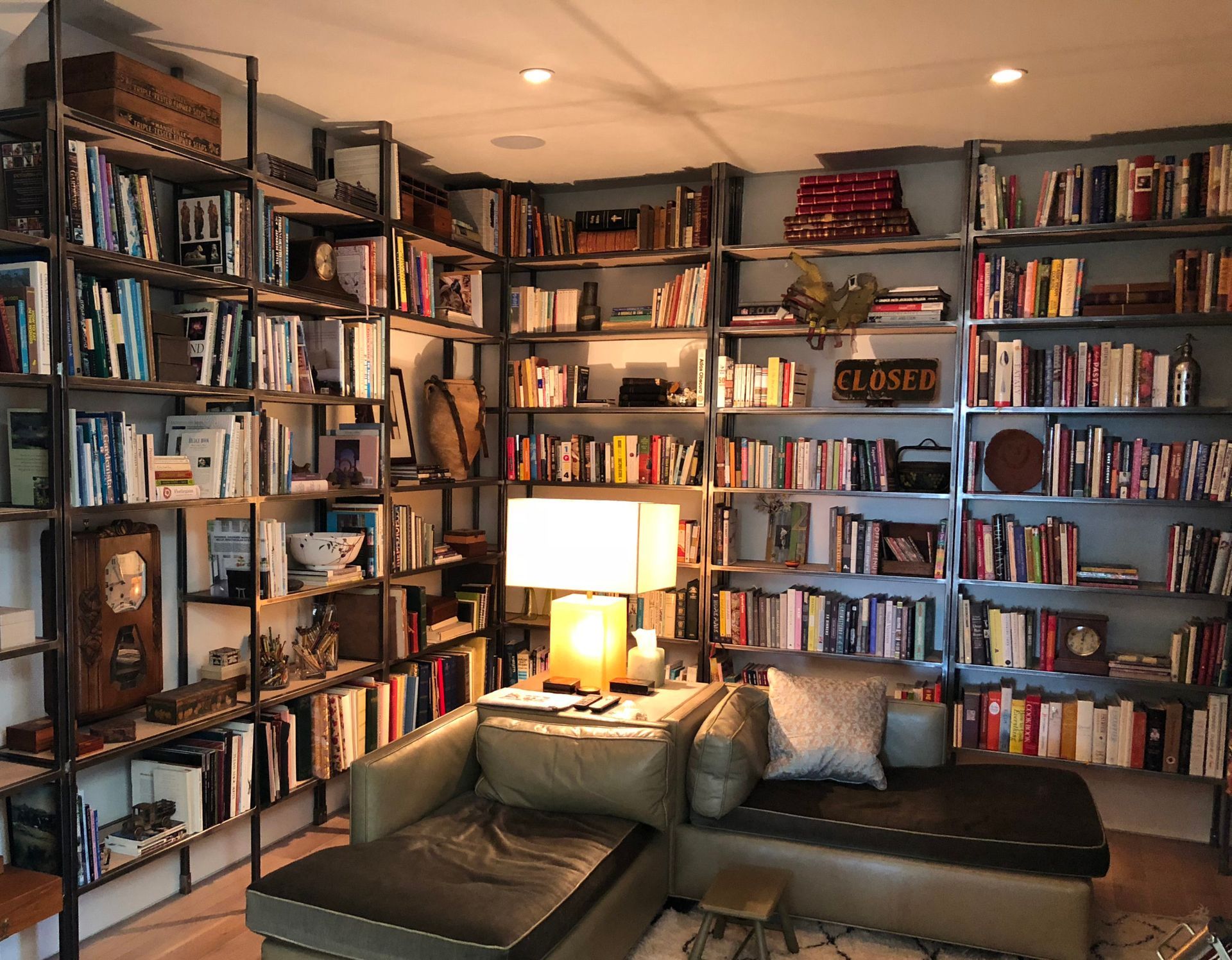 Cozy library corner with built-in bookshelves filled with books, leather couch, and warm lighting.