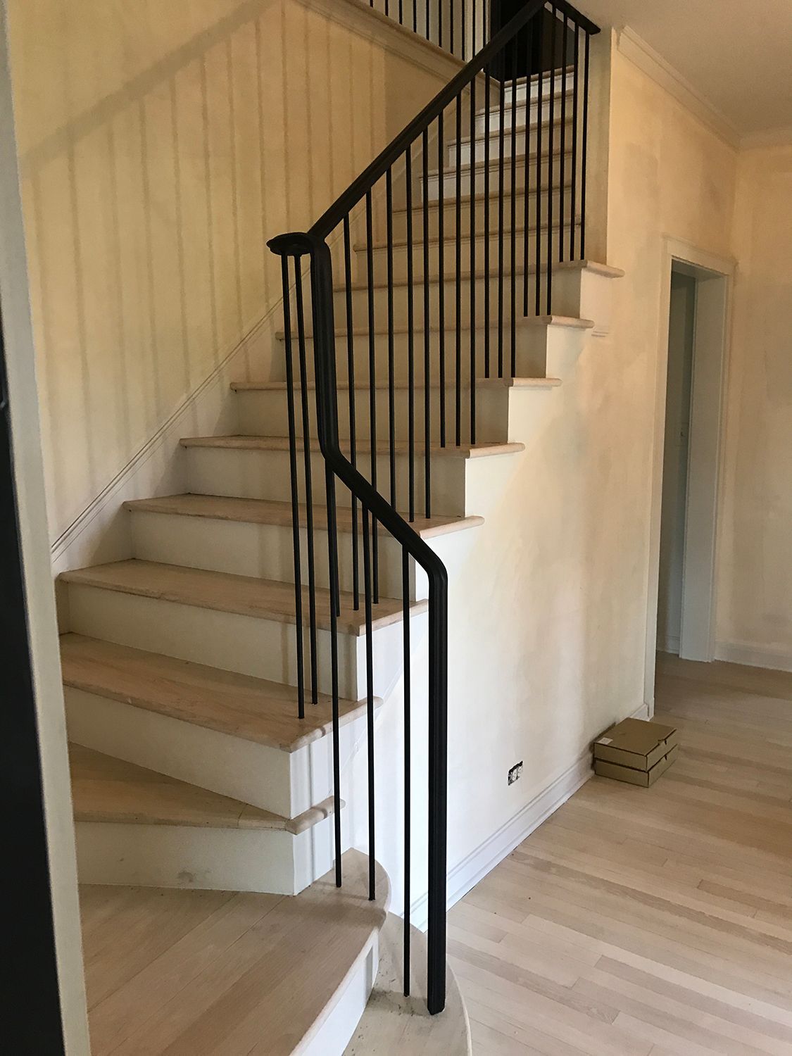 Staircase with wooden steps and black metal railing in a light-colored interior.