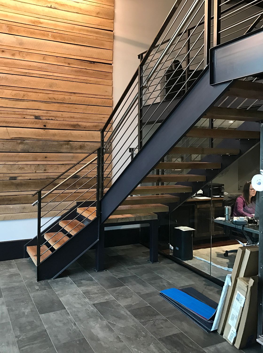 Staircase with wooden steps and metal railing in an office setting, wood-paneled wall.