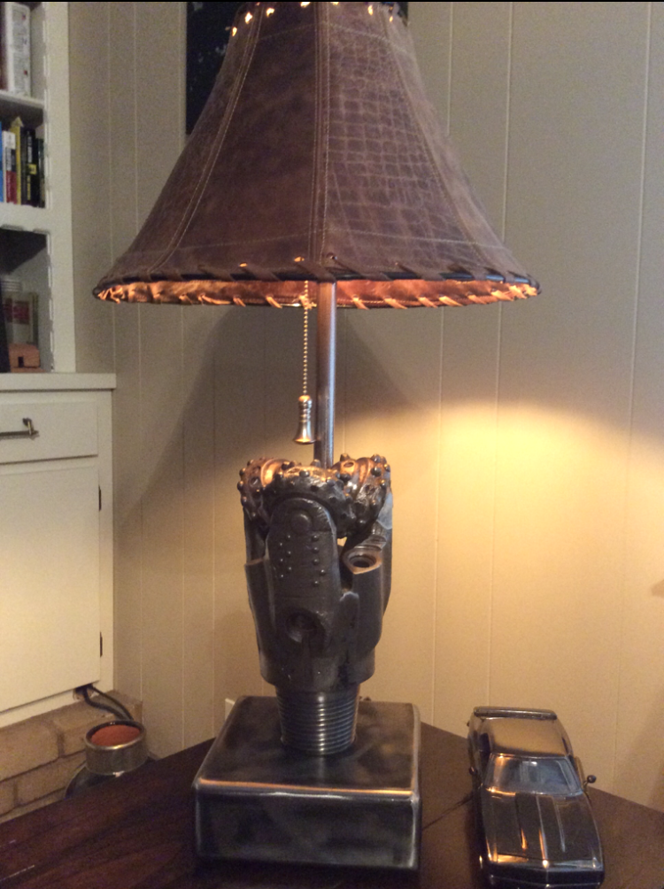 Metal lamp with a brown lampshade, sitting on a table, with a small toy car next to it.