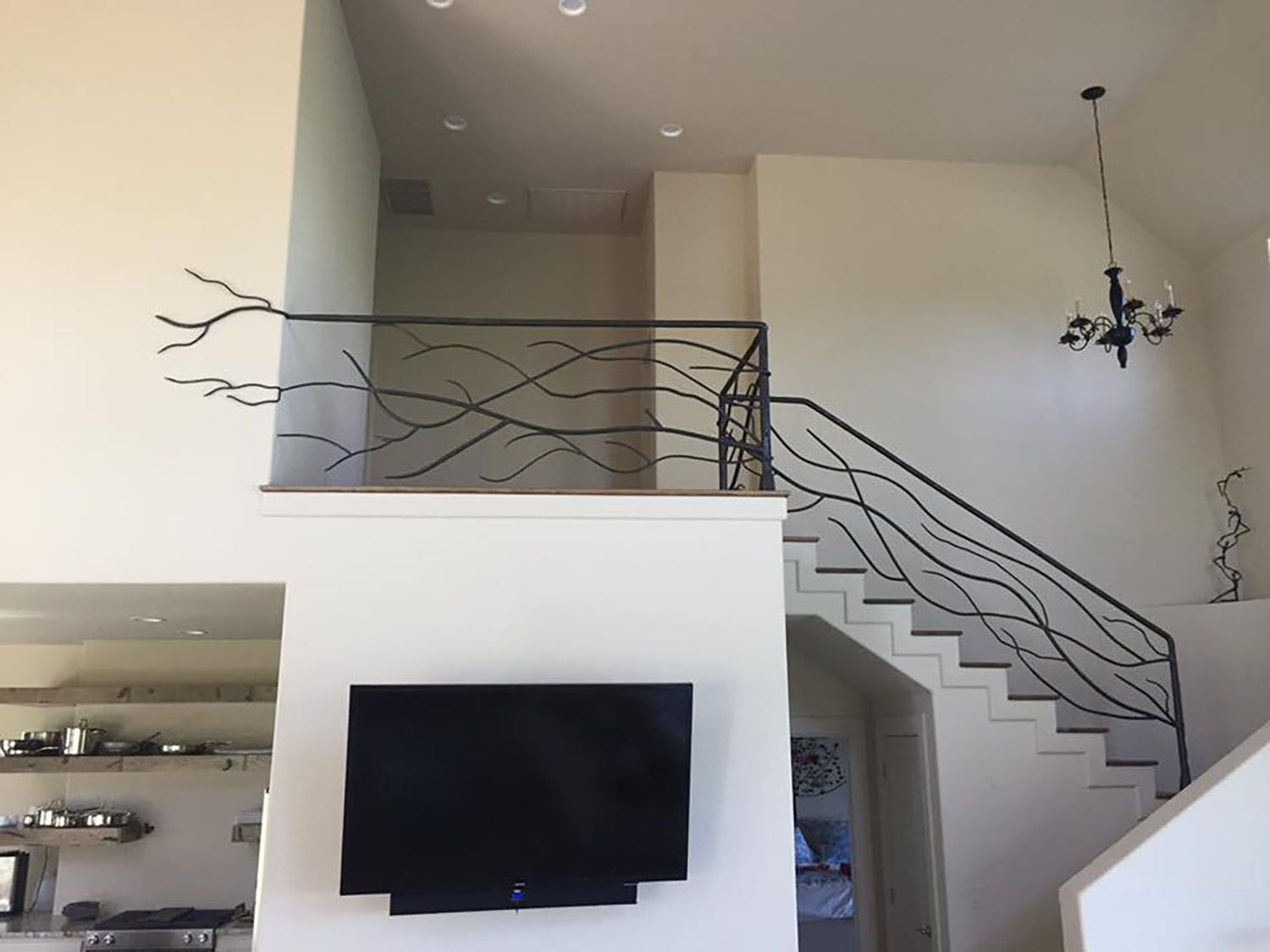 Staircase with black metal railing in a home. The railing design mimics tree branches.