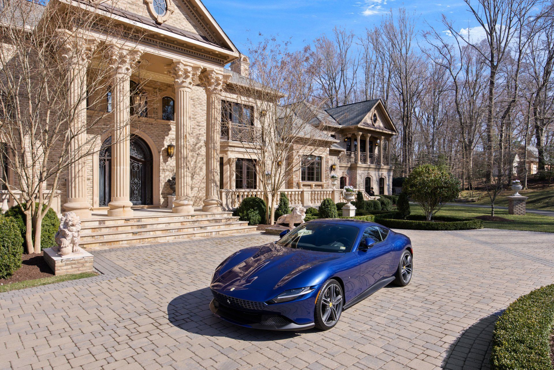 A blue sports car is parked in front of a large mansion shoot by Craig Westerman.