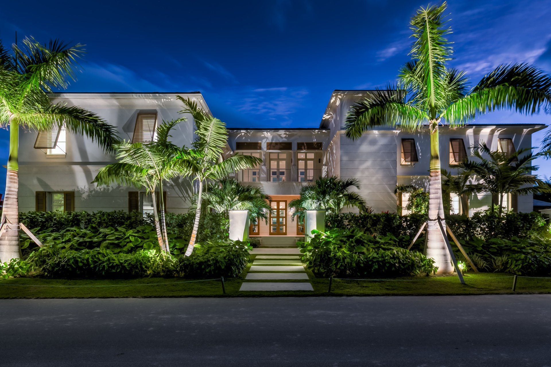 A large white house with palm trees in front of it at night - twilight shoot by Craig Westerman