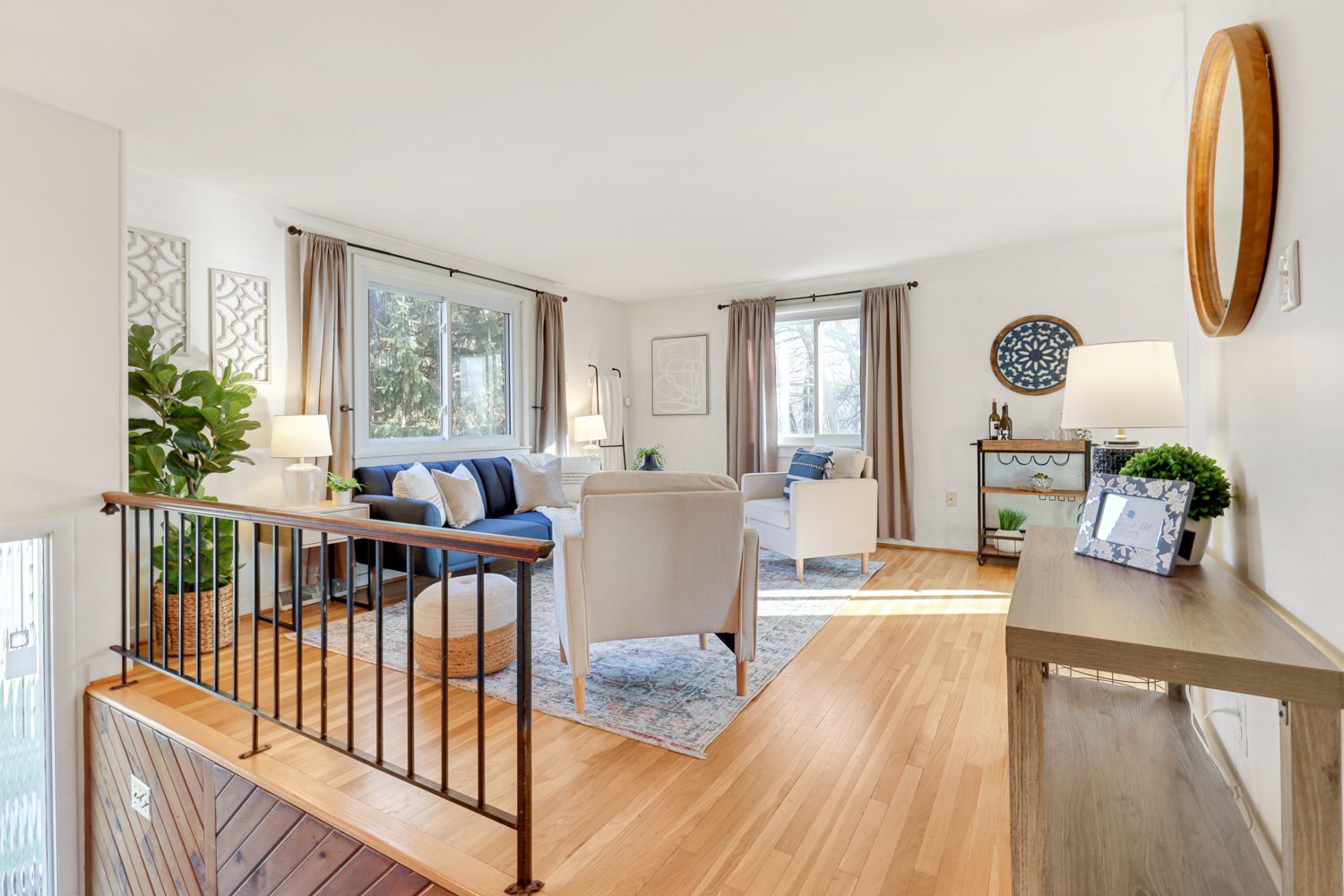 A living room with hardwood floors , a couch , chairs , and a mirror.Shoot by Hometrack.