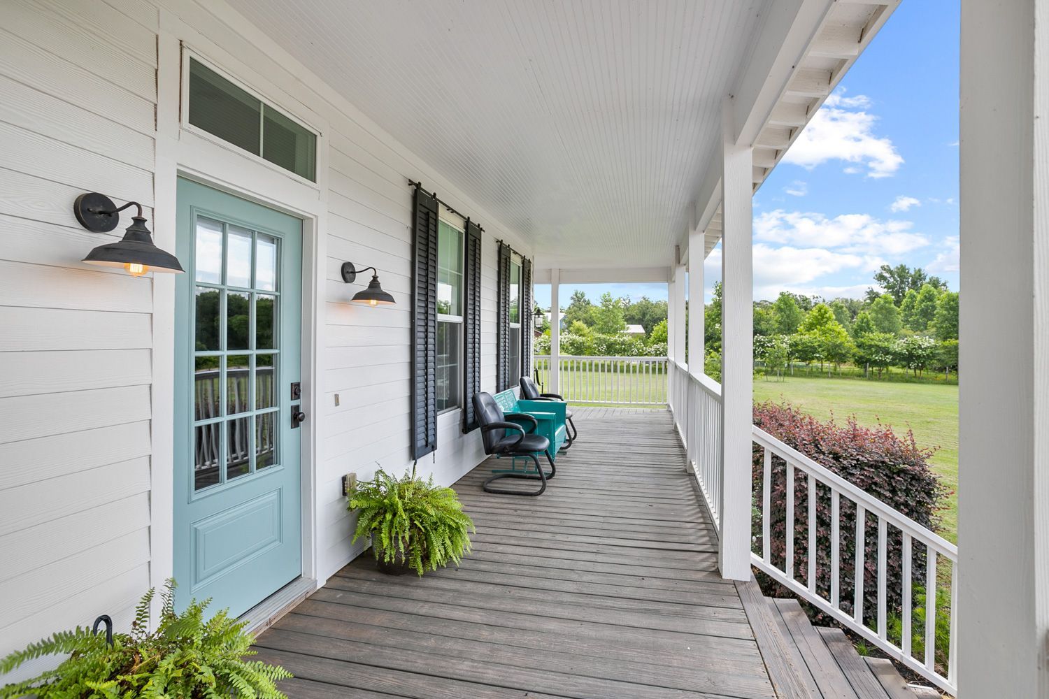 A white house with a blue door and a large porch in Houston Texas by Craig westerman and team.