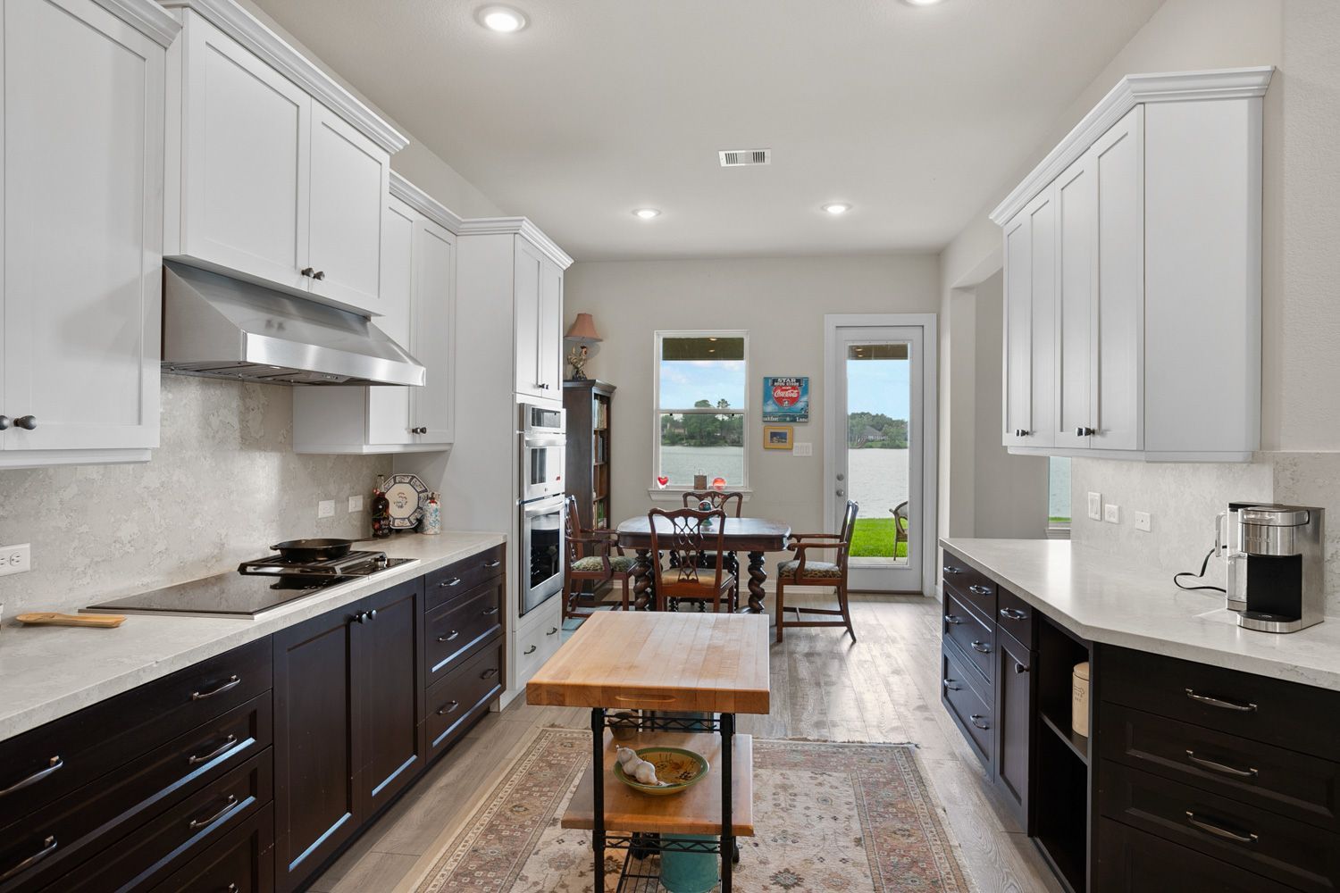 Houston Tx kitchen with white cabinets and black drawers and a wooden table by Hometrack team