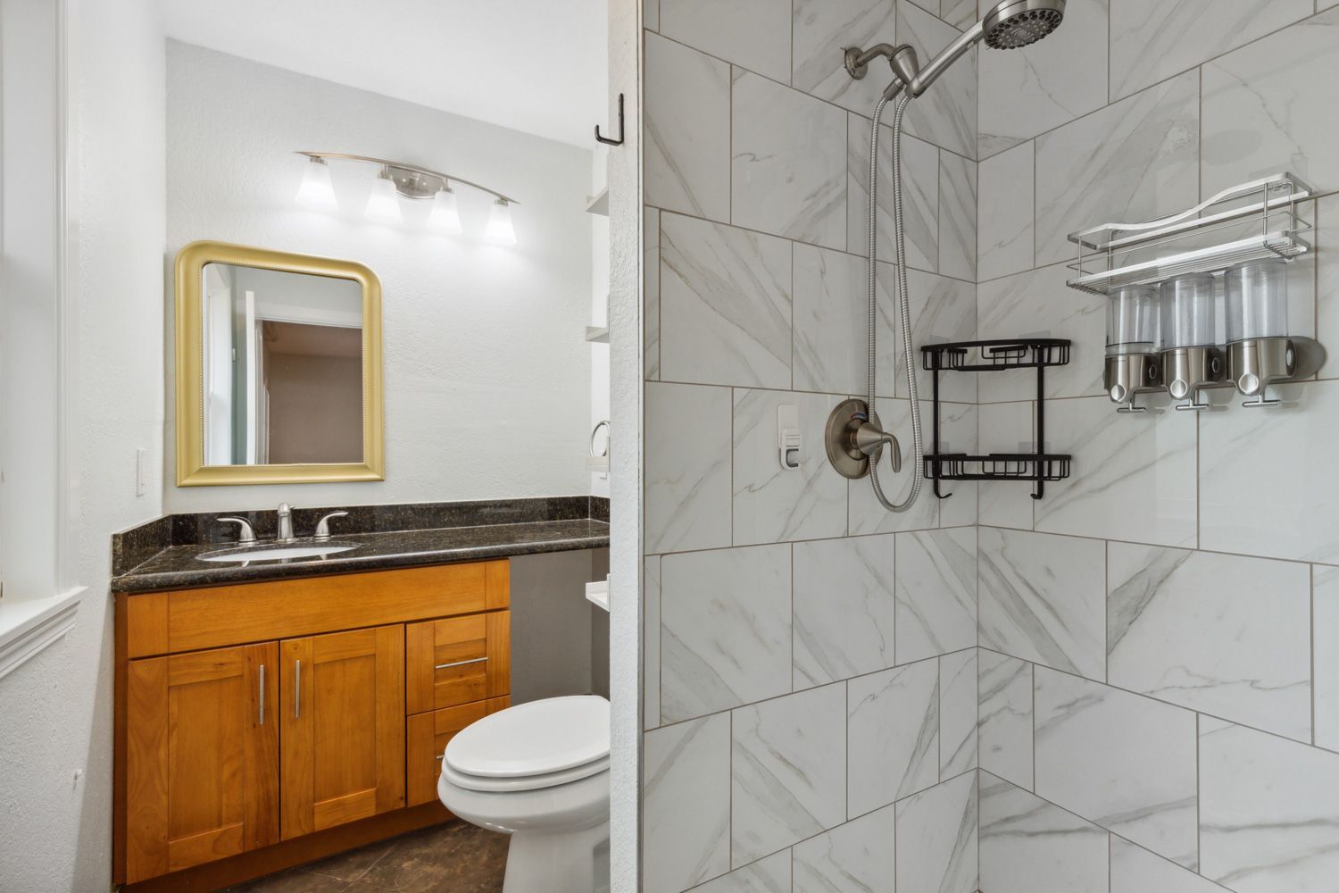 A bathroom with a toilet , sink , mirror and tiled shower walls in Seattle. Shoot by Craig Westerman and the Hometrack Team.