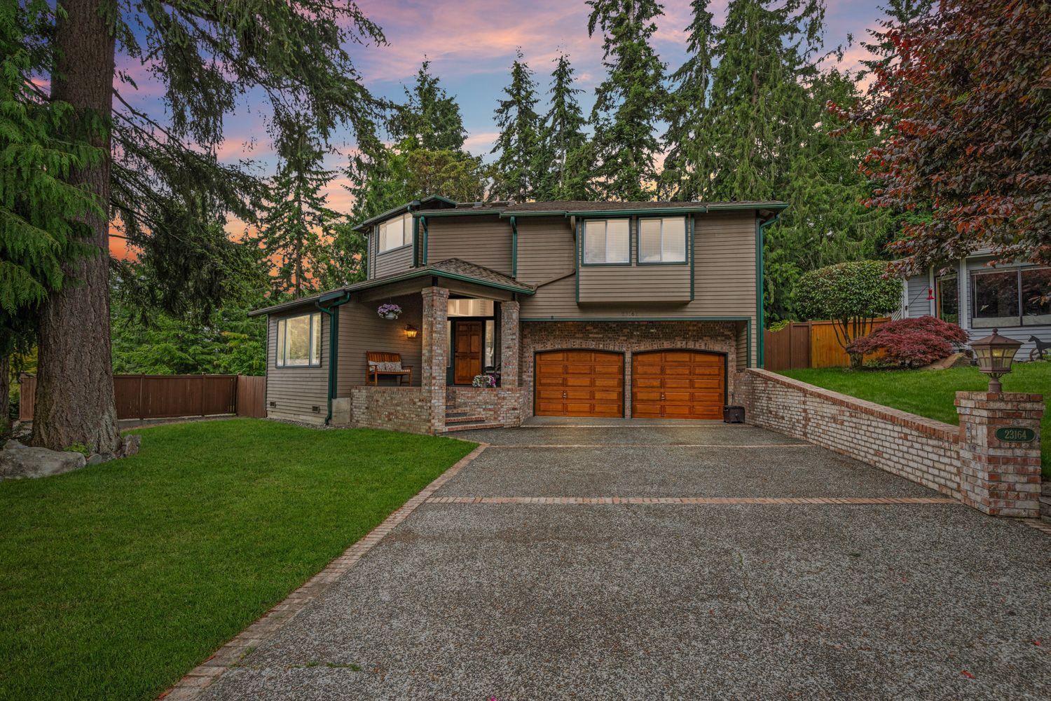 Seattle, Washington - A large house with two garages and a driveway surrounded by tree shoot by Hometrack Team.