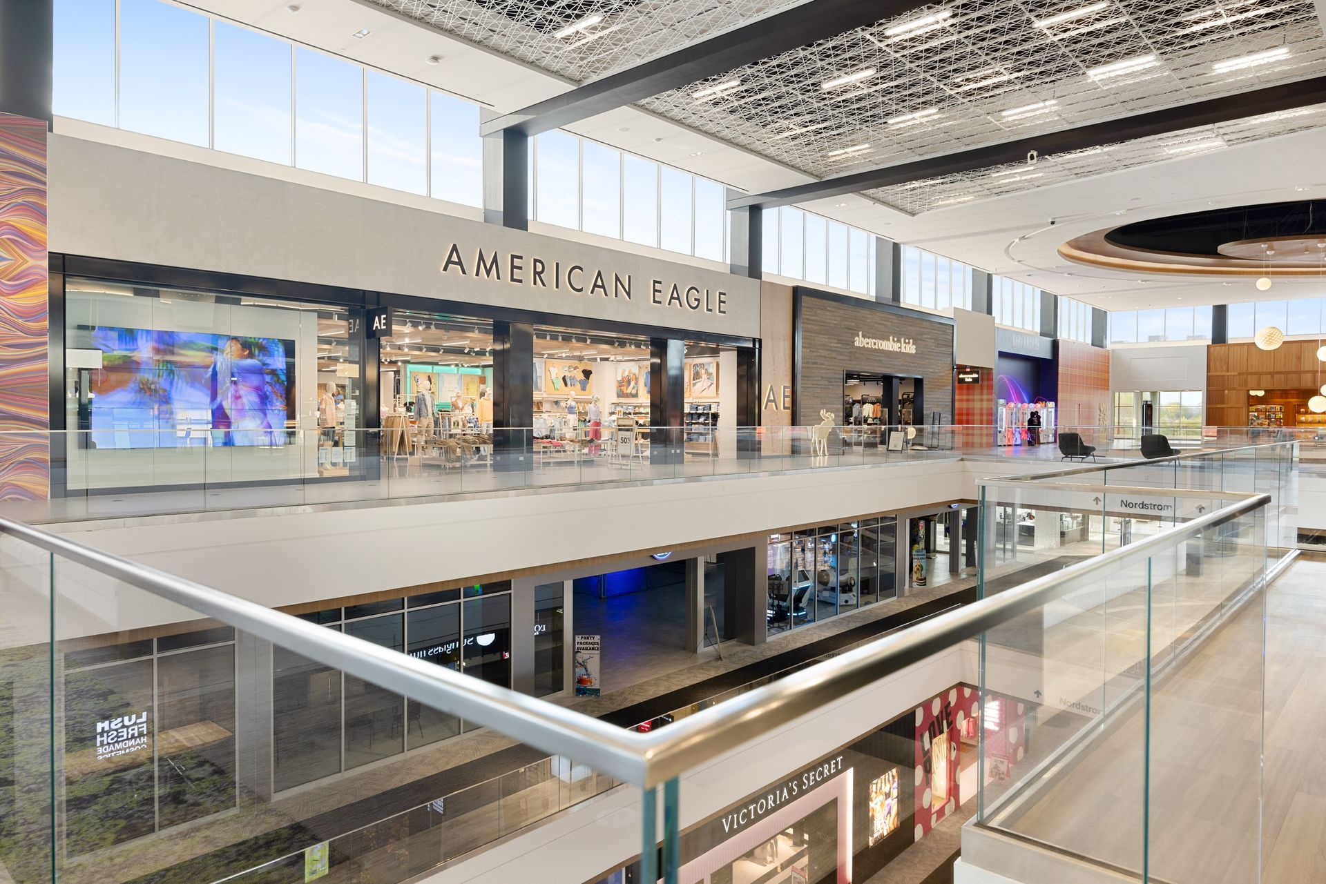 A large shopping mall with a glass railing and lots of windows.