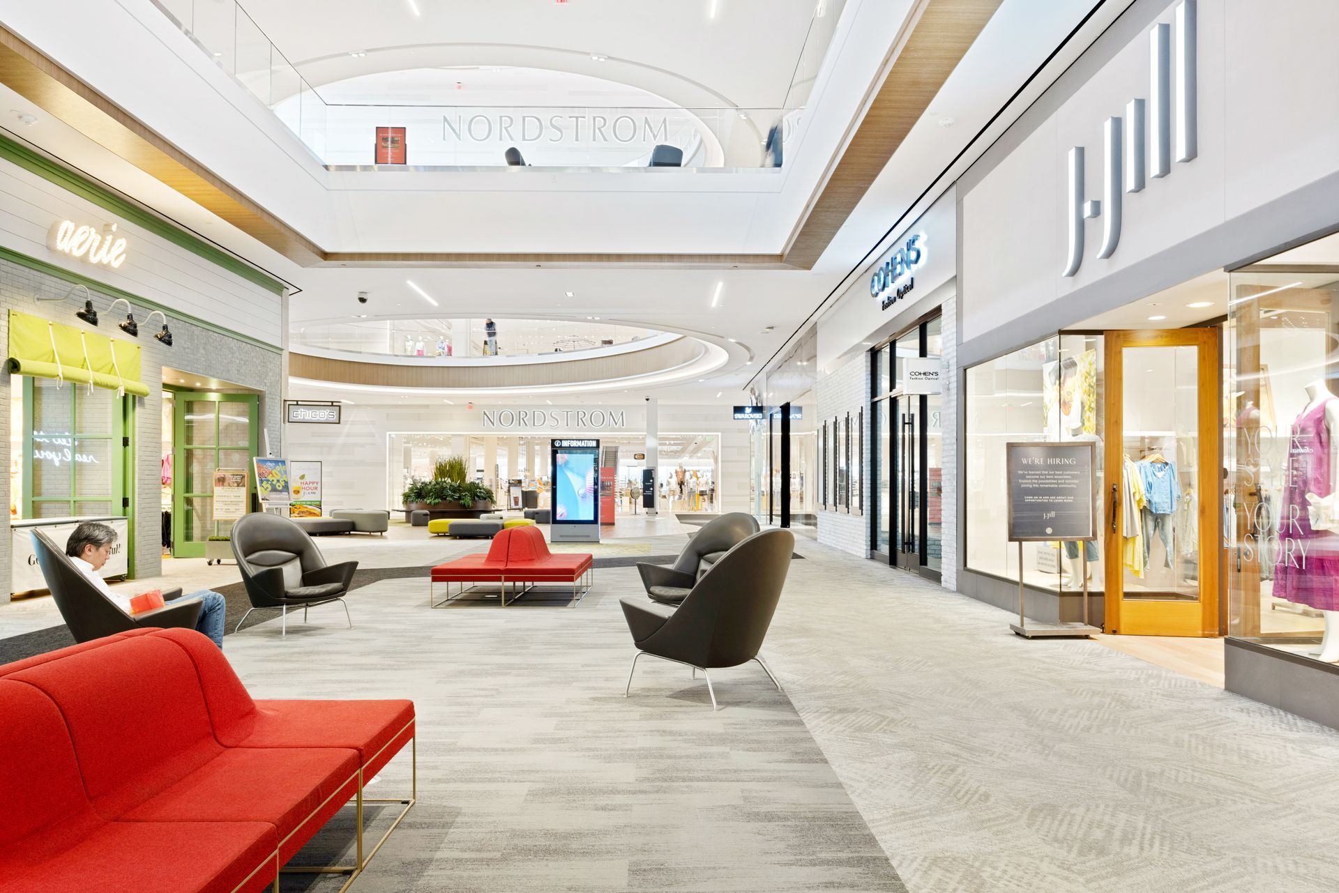 A shopping mall with a lot of furniture and chairs in it.