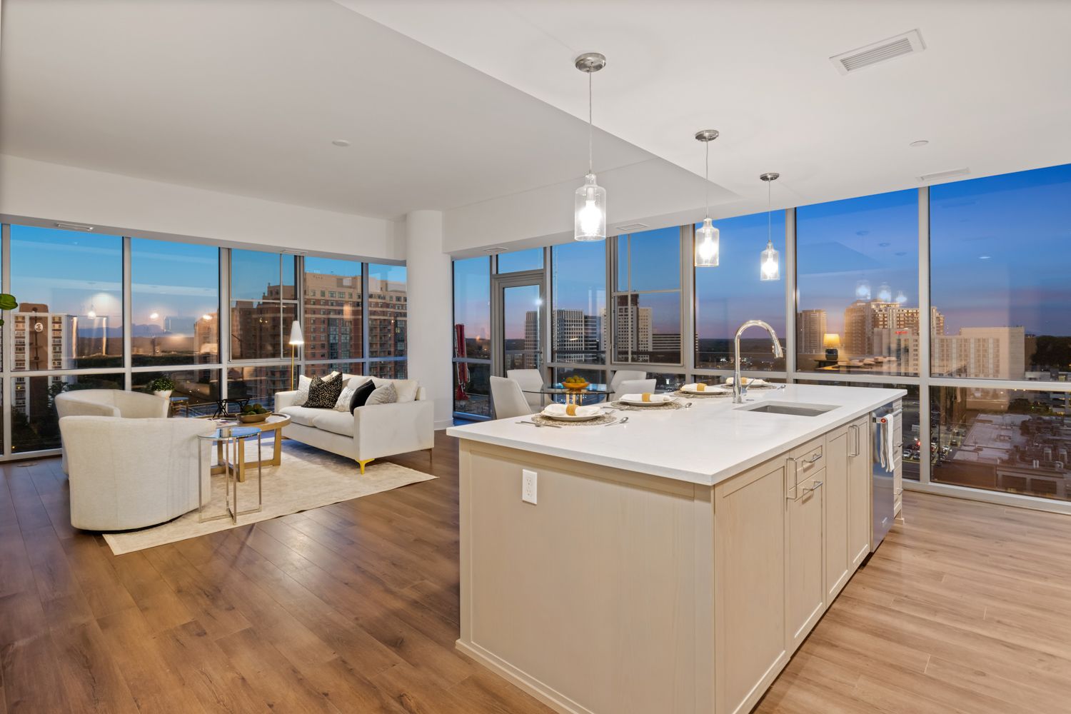 a living room and kitchen in a large apartment with lots of windows Apartment overlooking city - Twilight shoot by Craig Westerman