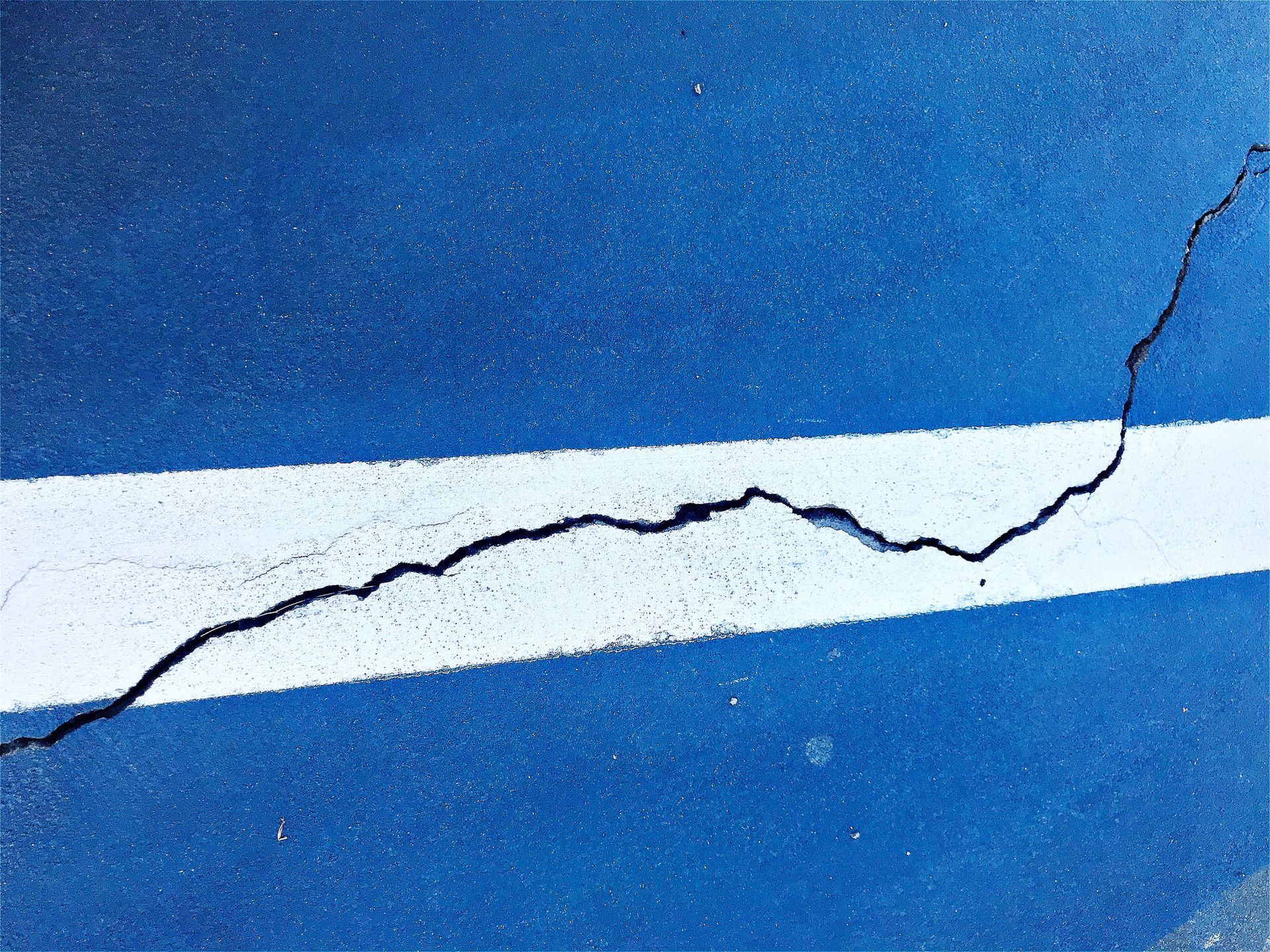 Cracked white wall, long diagonal fissures with dark shading.