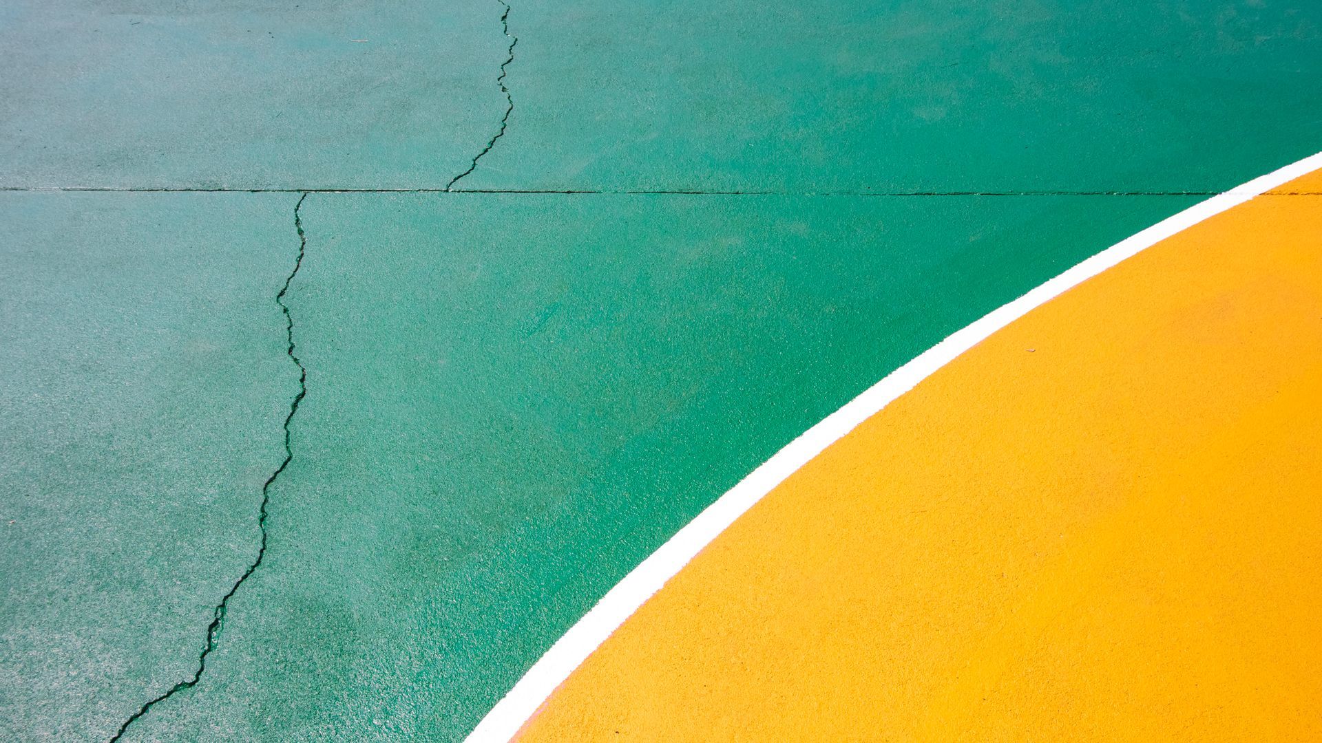 Cracked, overgrown tennis court with weeds; net and basketball hoop visible in outdoor setting.
