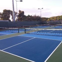 Blue and green tennis courts, nets in place, outdoor setting.