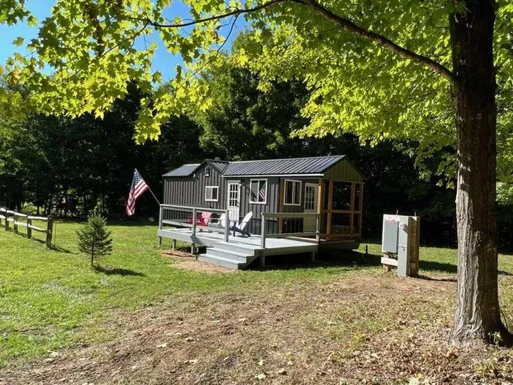 A small house is sitting in the middle of a grassy field.