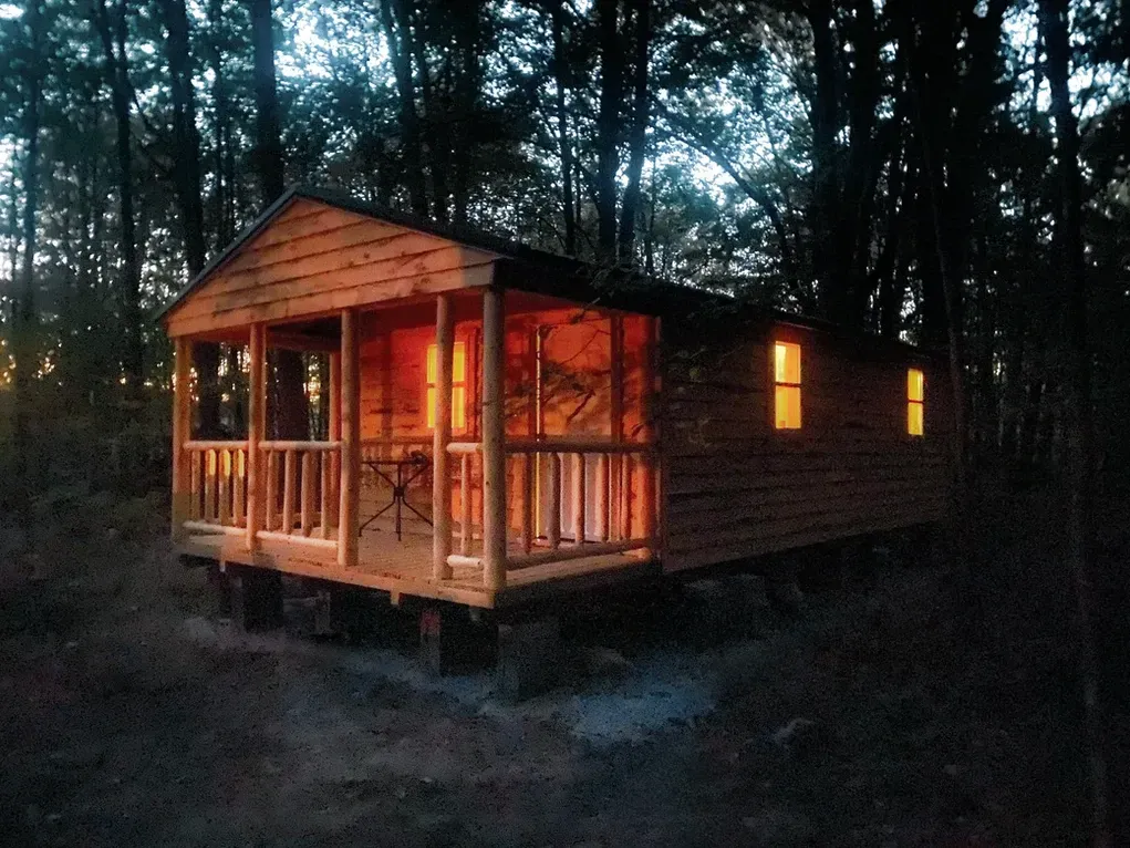 A small cabin in the middle of a forest at night