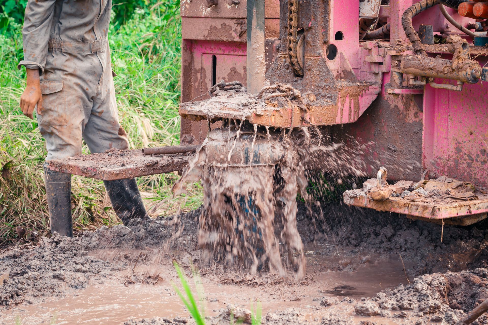 A worker operates a large industrial water well drilling machine for water extraction.