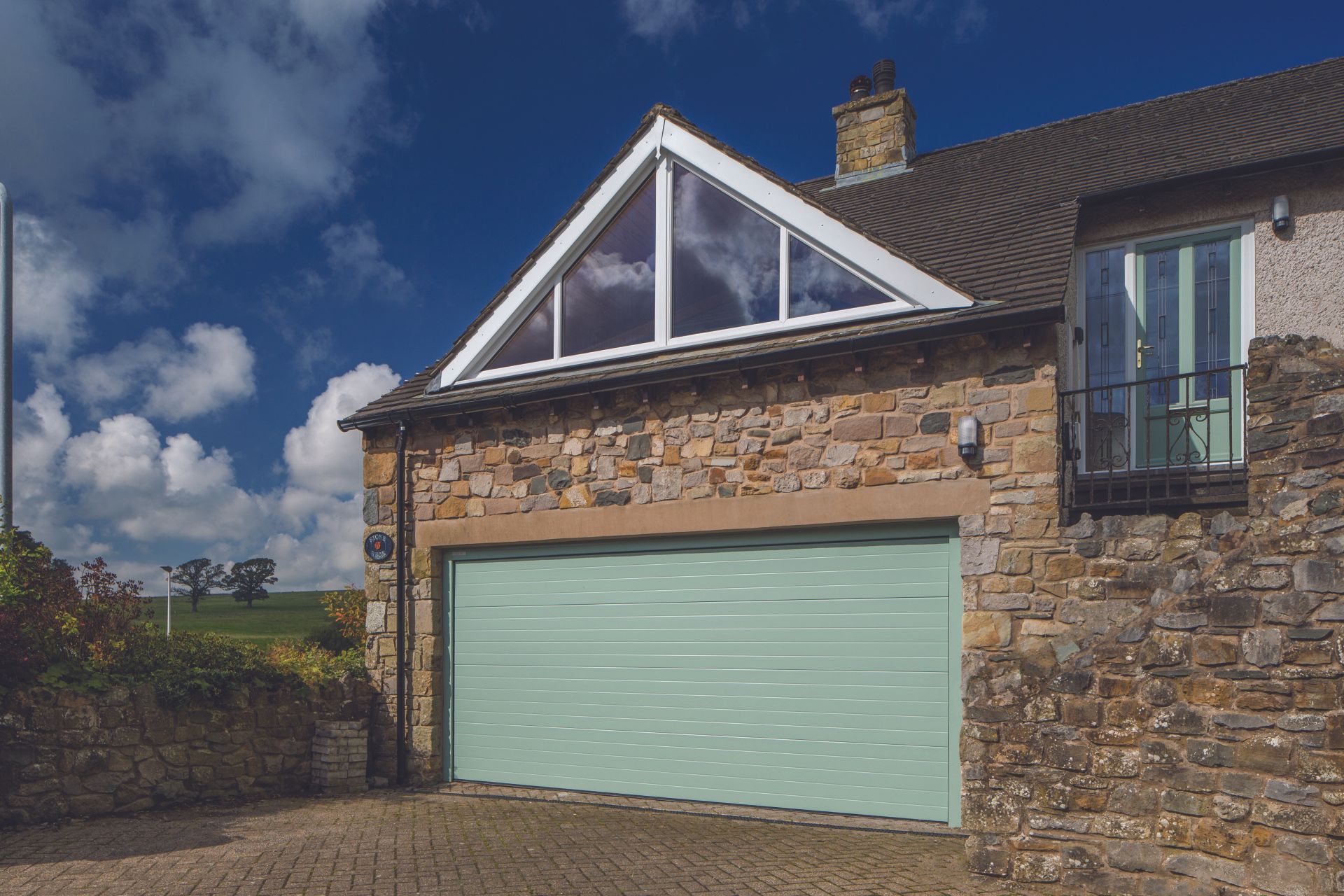 A newly fitted green garage door on a farmhouse