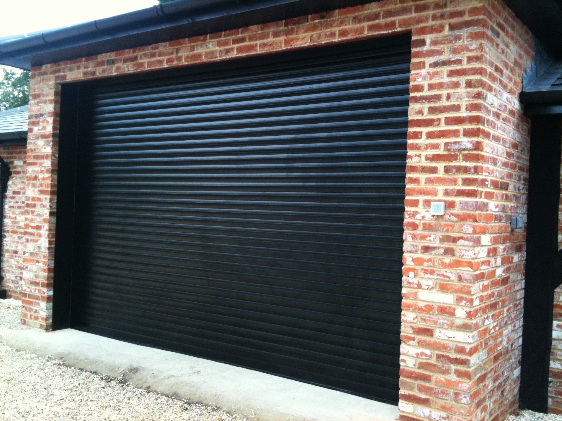 A newly fitted black garage rolling door attached to a house