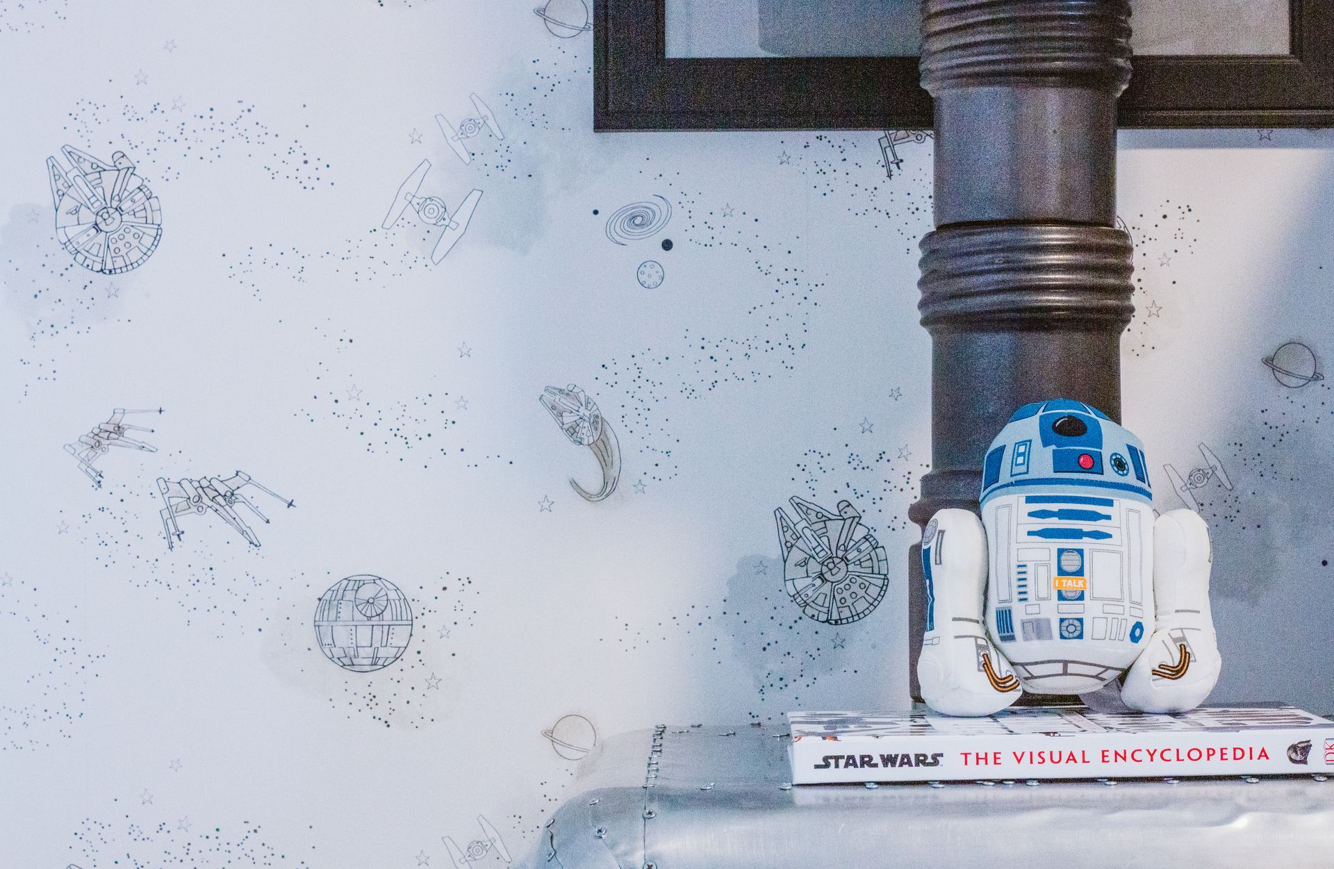 A r2d2 toy is sitting on top of a book titled star wars