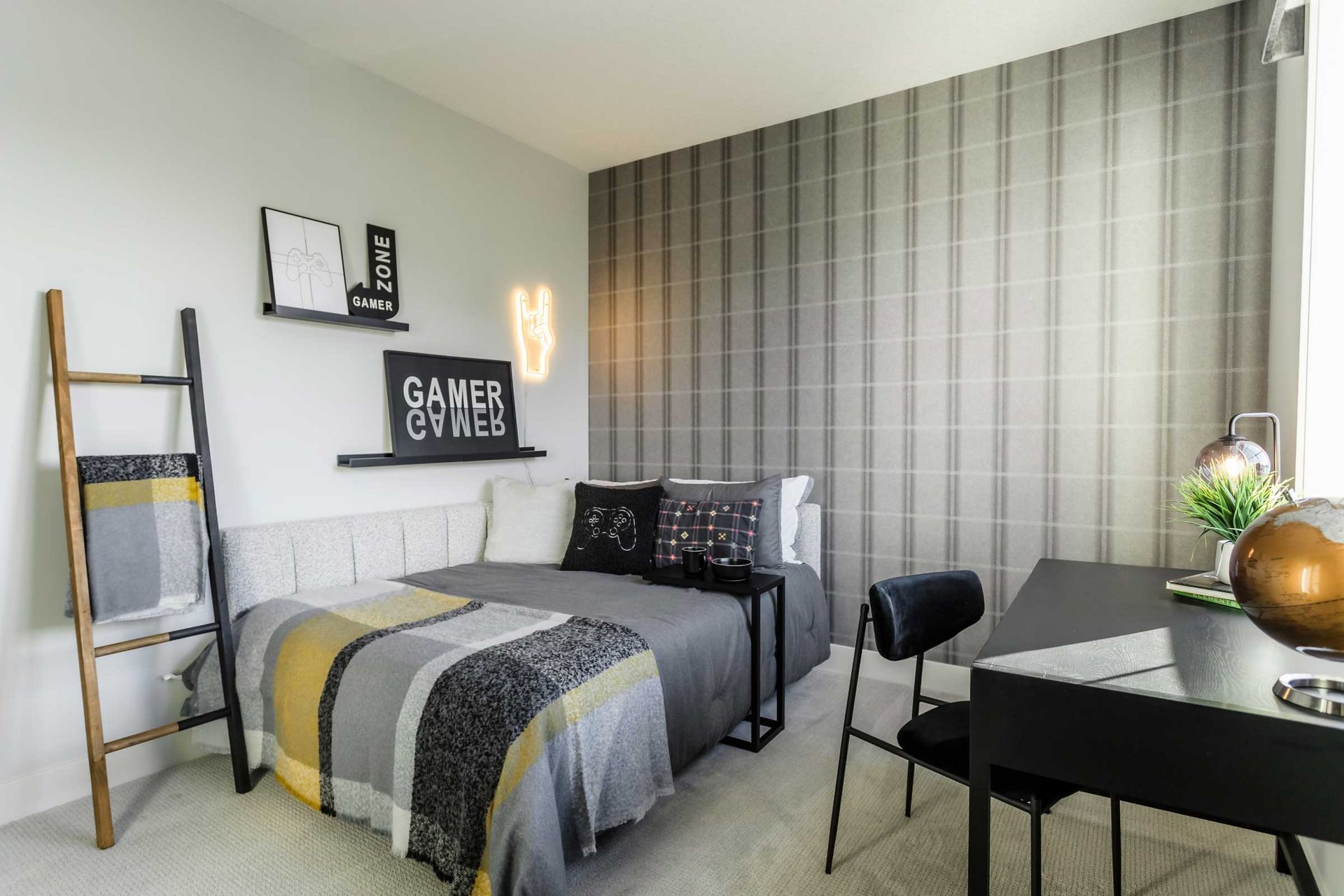 A bedroom with a bed , desk , chairs and a ladder.