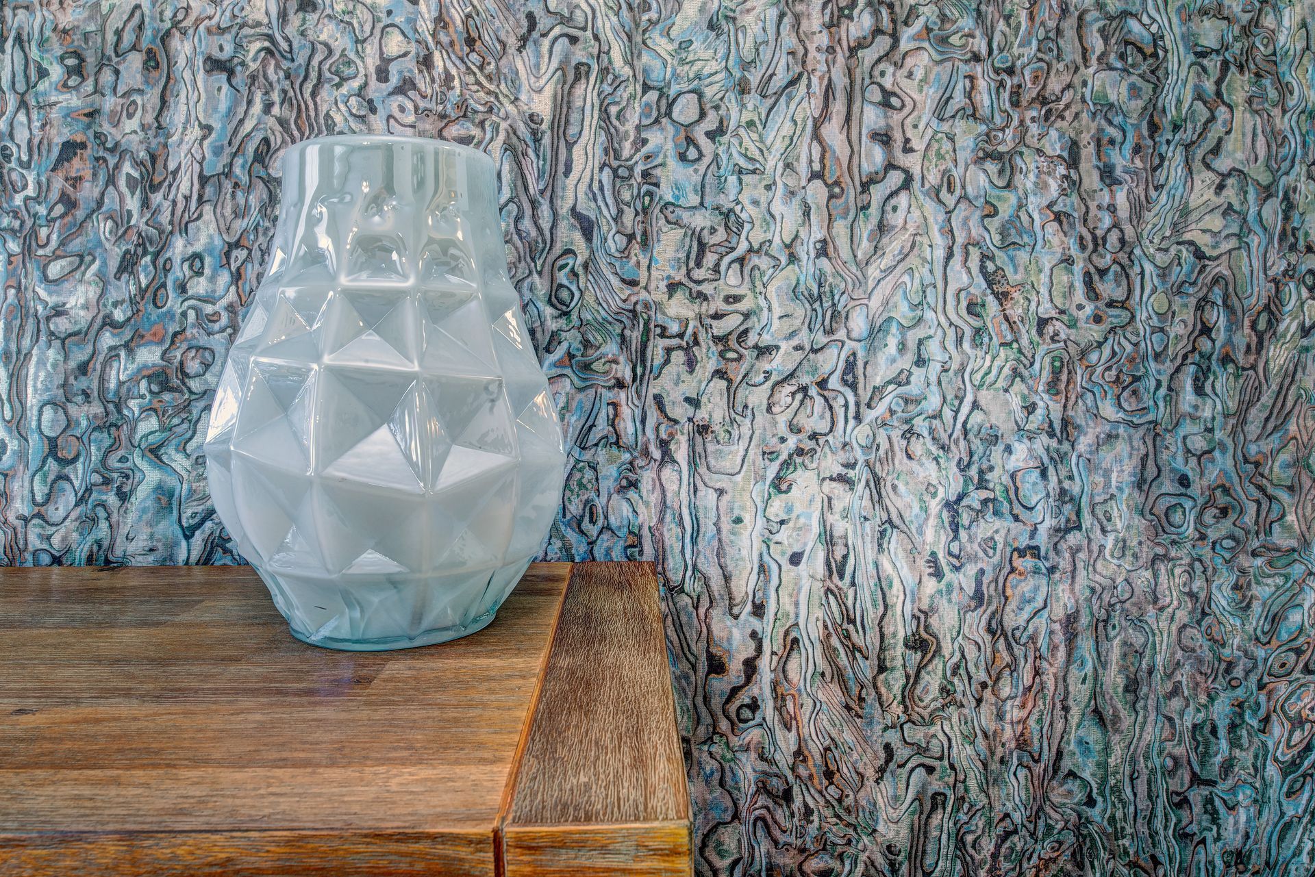 A vase is sitting on a wooden table in front of a wall.