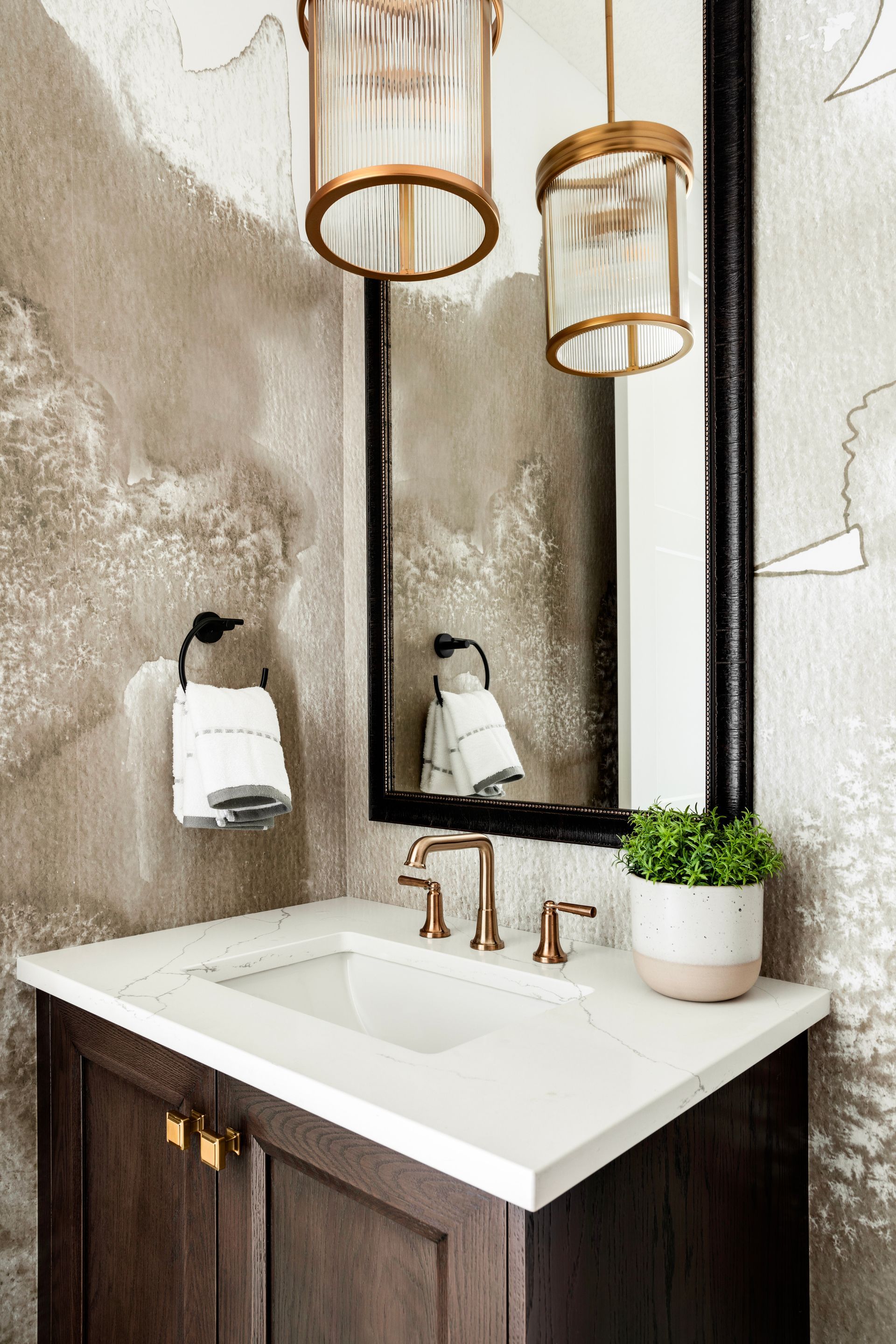 A bathroom with a sink , mirror and lanterns hanging from the ceiling.