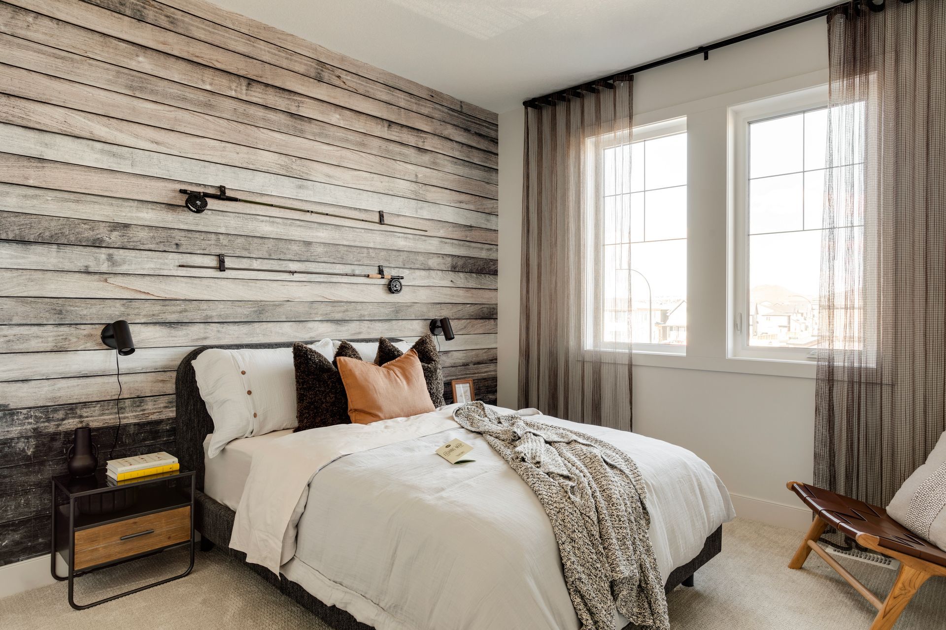 A bedroom with a bed , nightstand , chair and wooden wall.