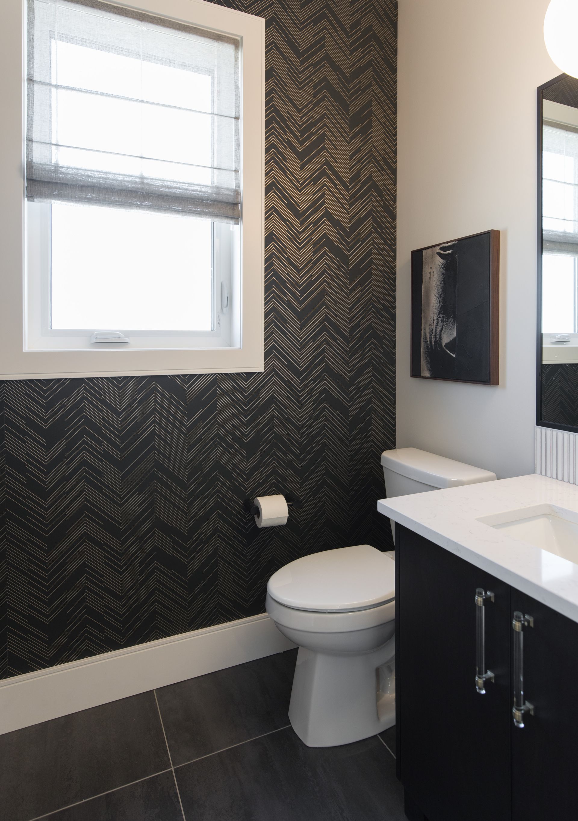 A bathroom with a toilet , sink , mirror and window.