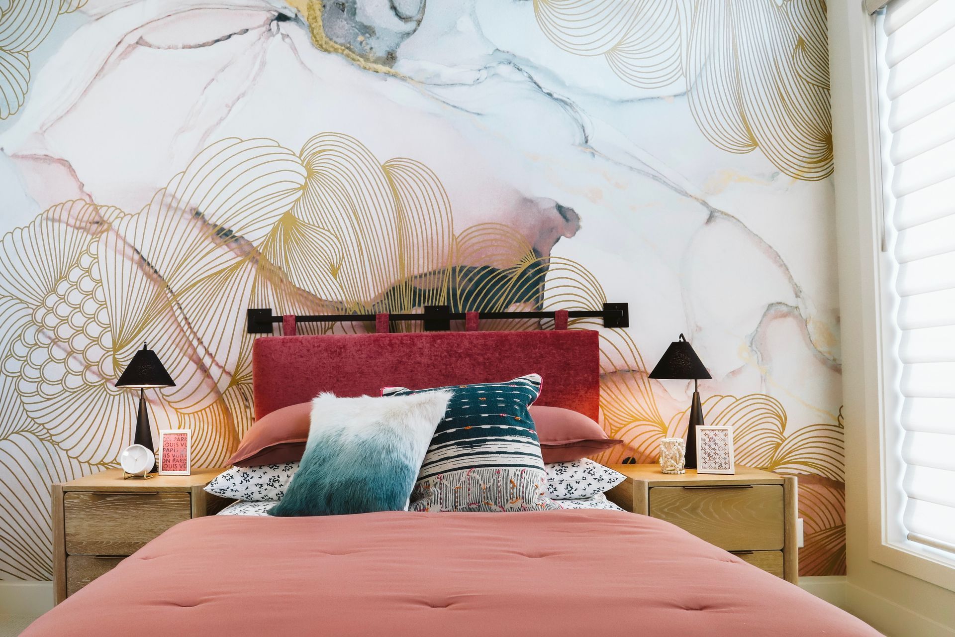 A bedroom with a bed , nightstands , lamps and a painting on the wall.