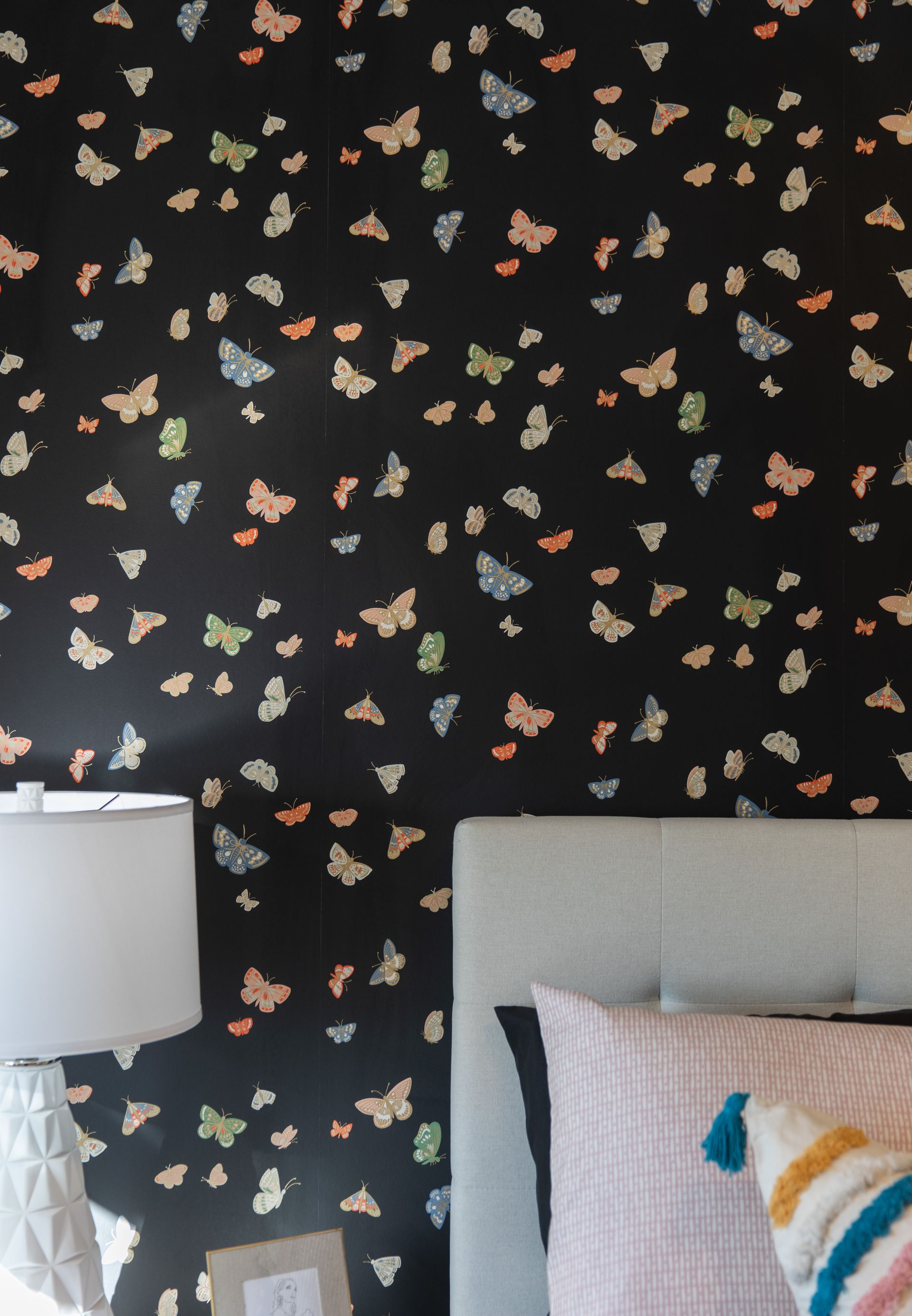 A bedroom with a black wall with butterflies on it