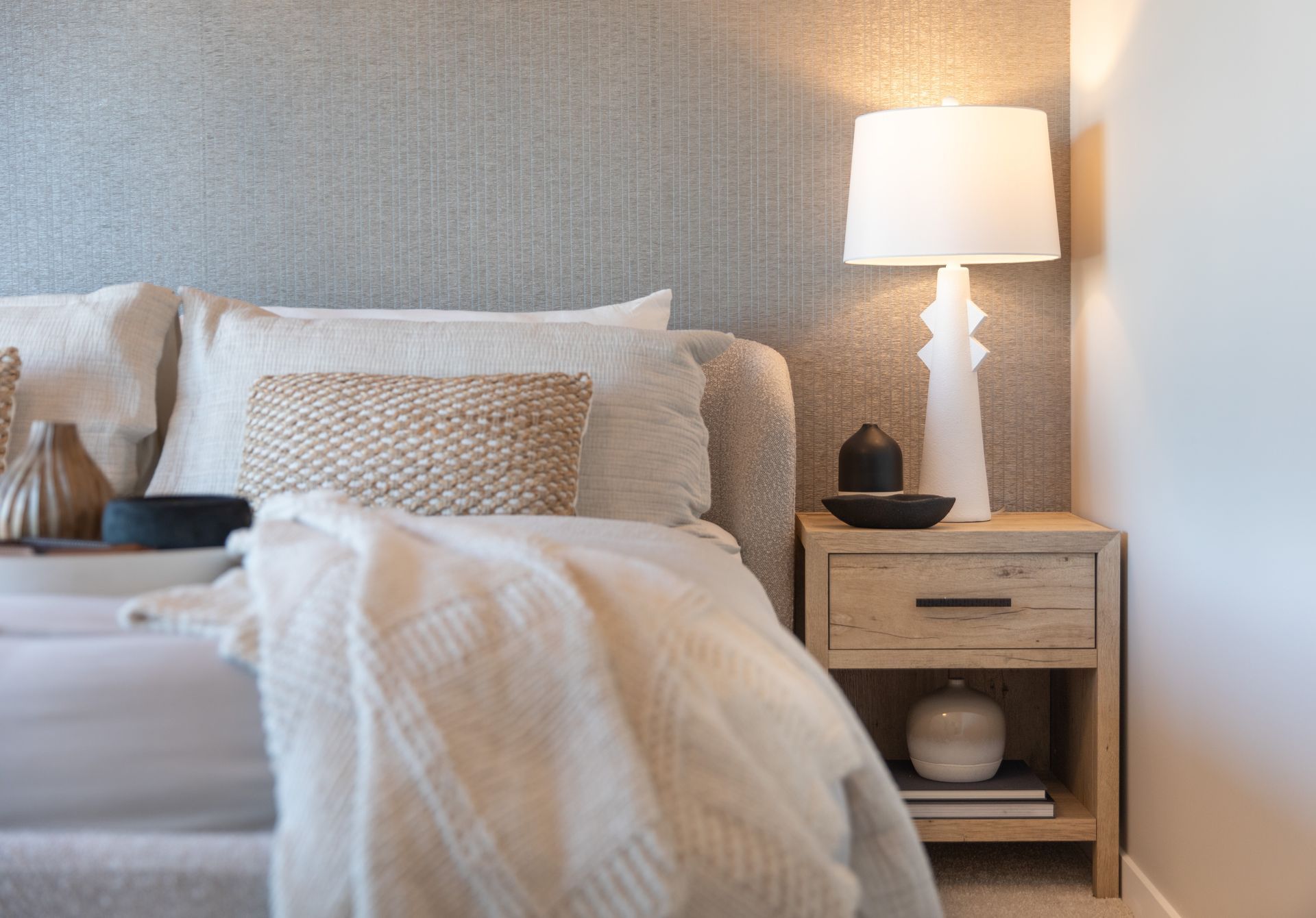 A bedroom with a bed , nightstand and lamp.