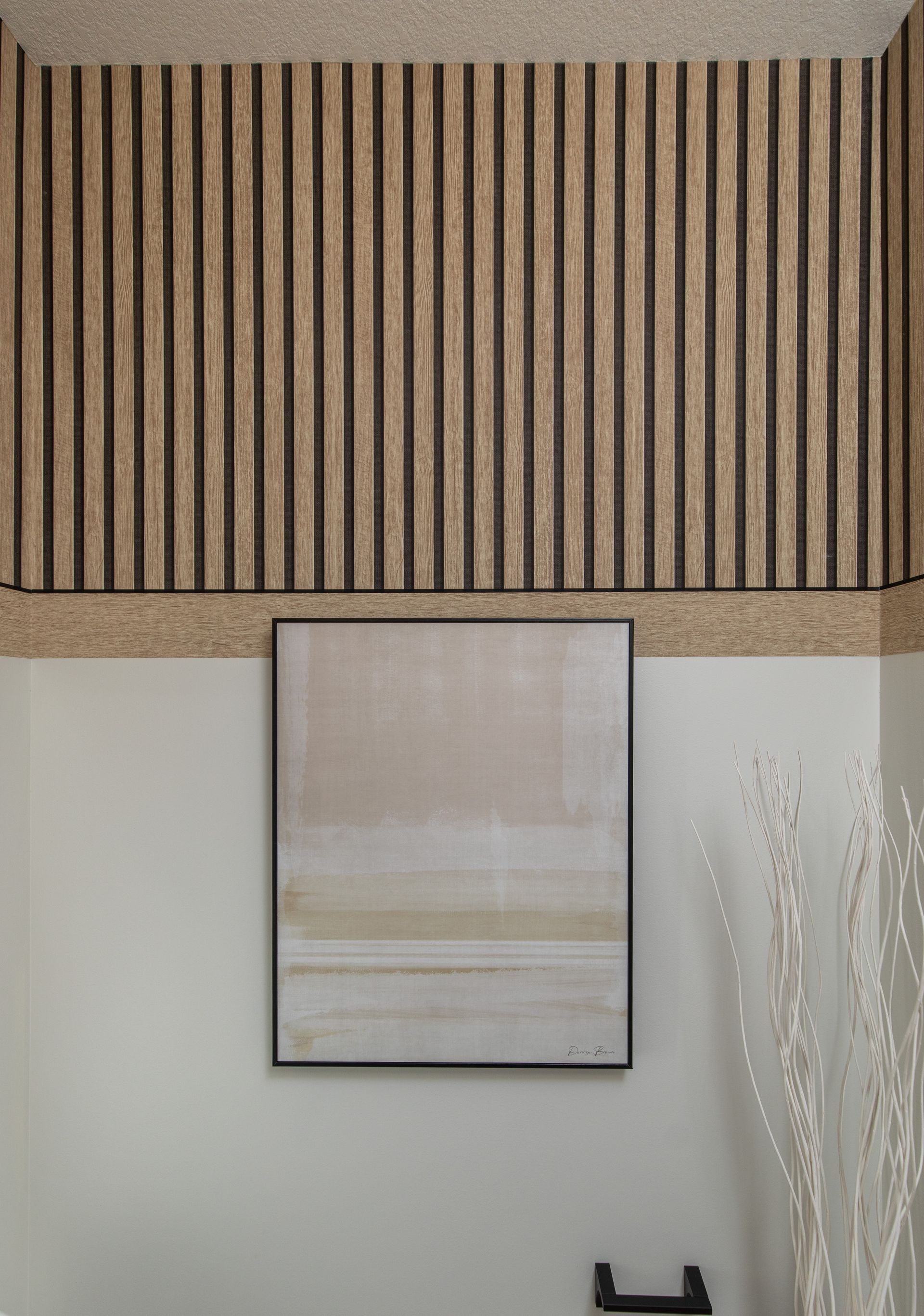 A painting is hanging on a wall next to a wooden wall.