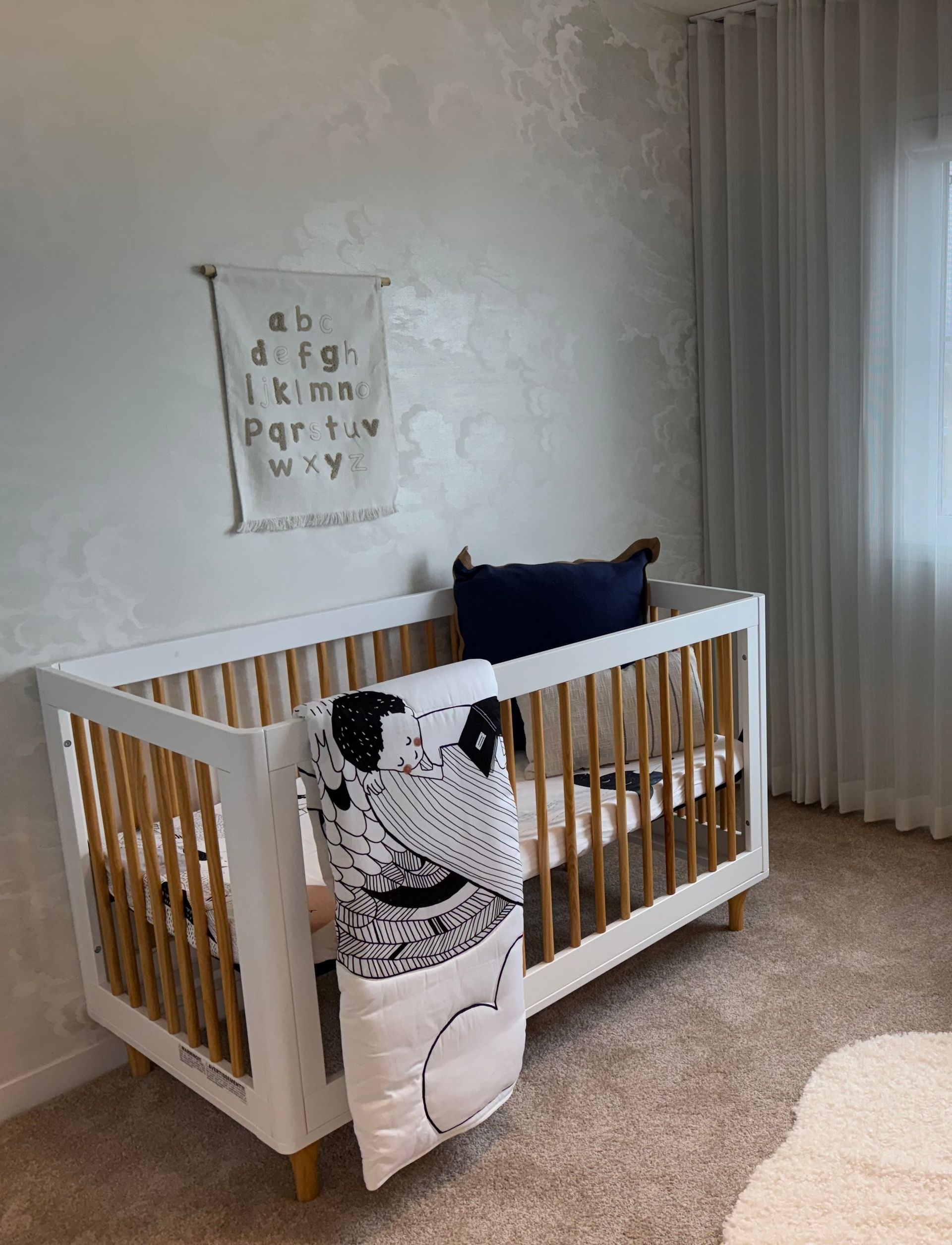 A white crib is sitting in a nursery next to a window.