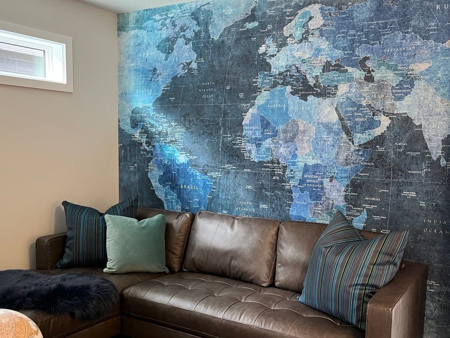 A living room with a couch and a map of the world on the wall.