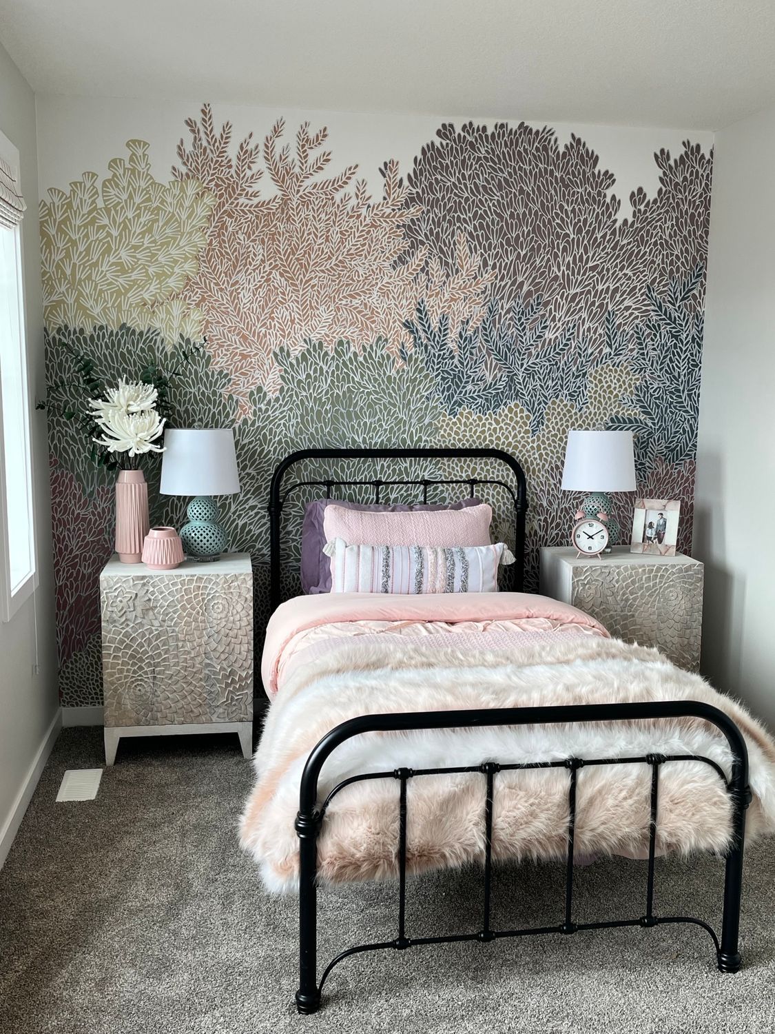 A bedroom with a bed , nightstands , lamps and a mural on the wall.