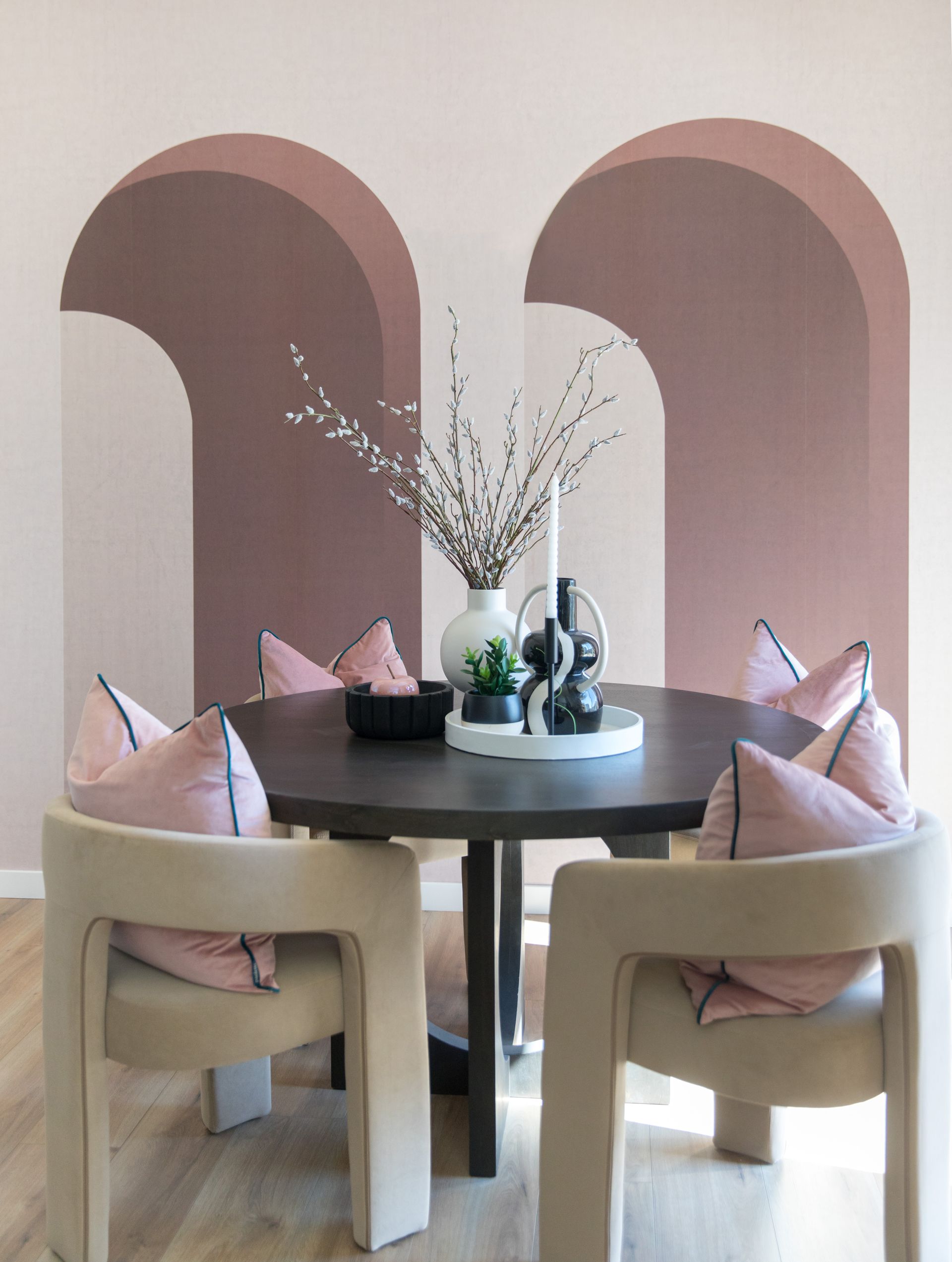 A dining room with a table and chairs and a vase of flowers on it.
