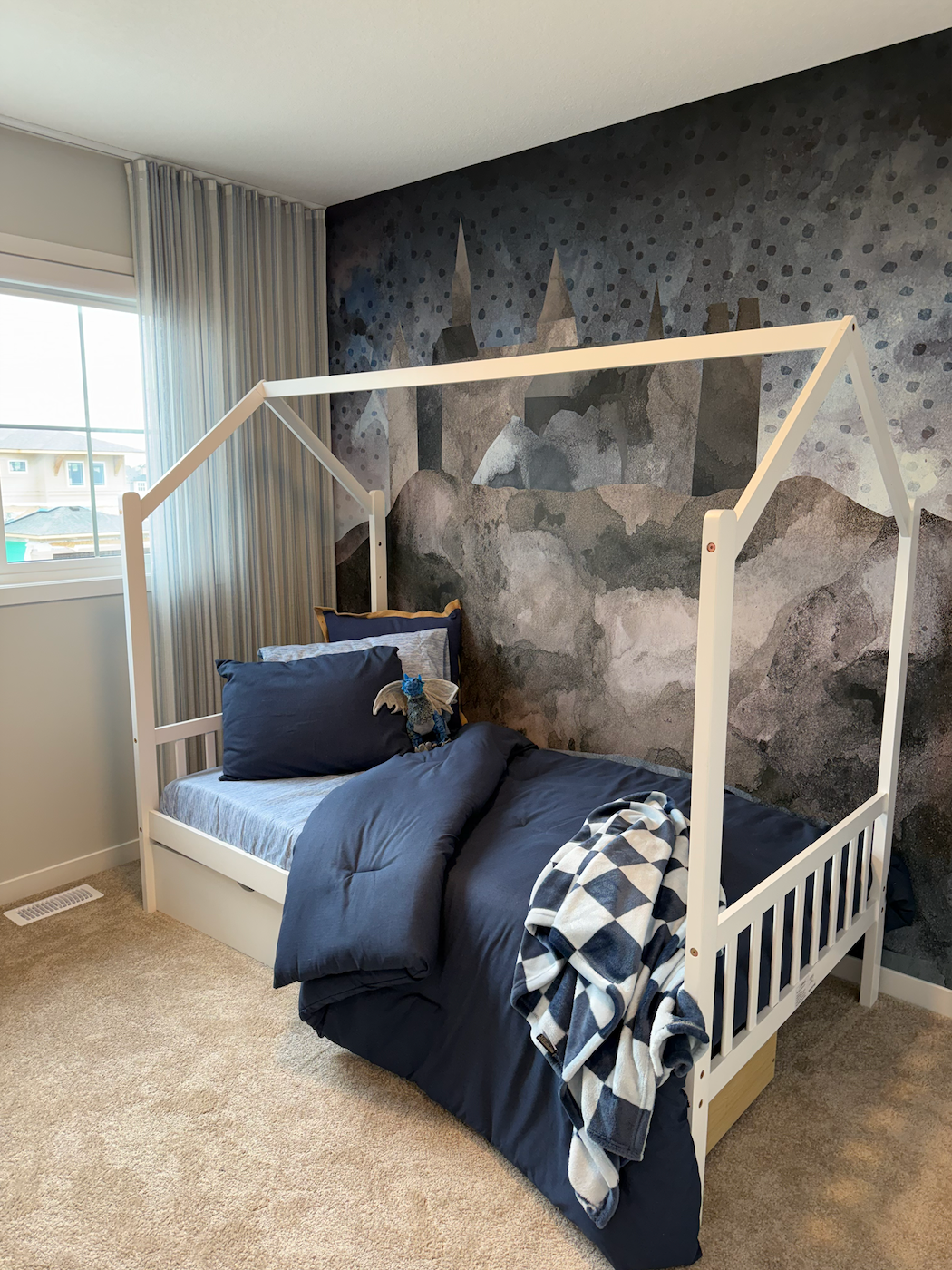 A bedroom with a canopy bed and a mural on the wall.