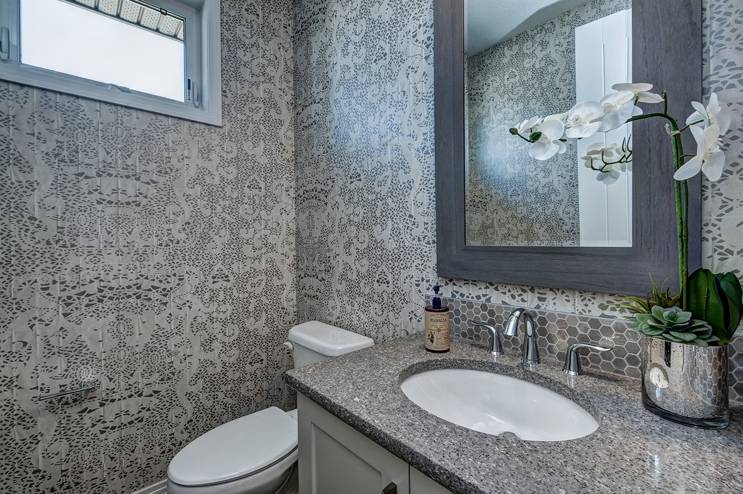 A bathroom with a toilet , sink and mirror.