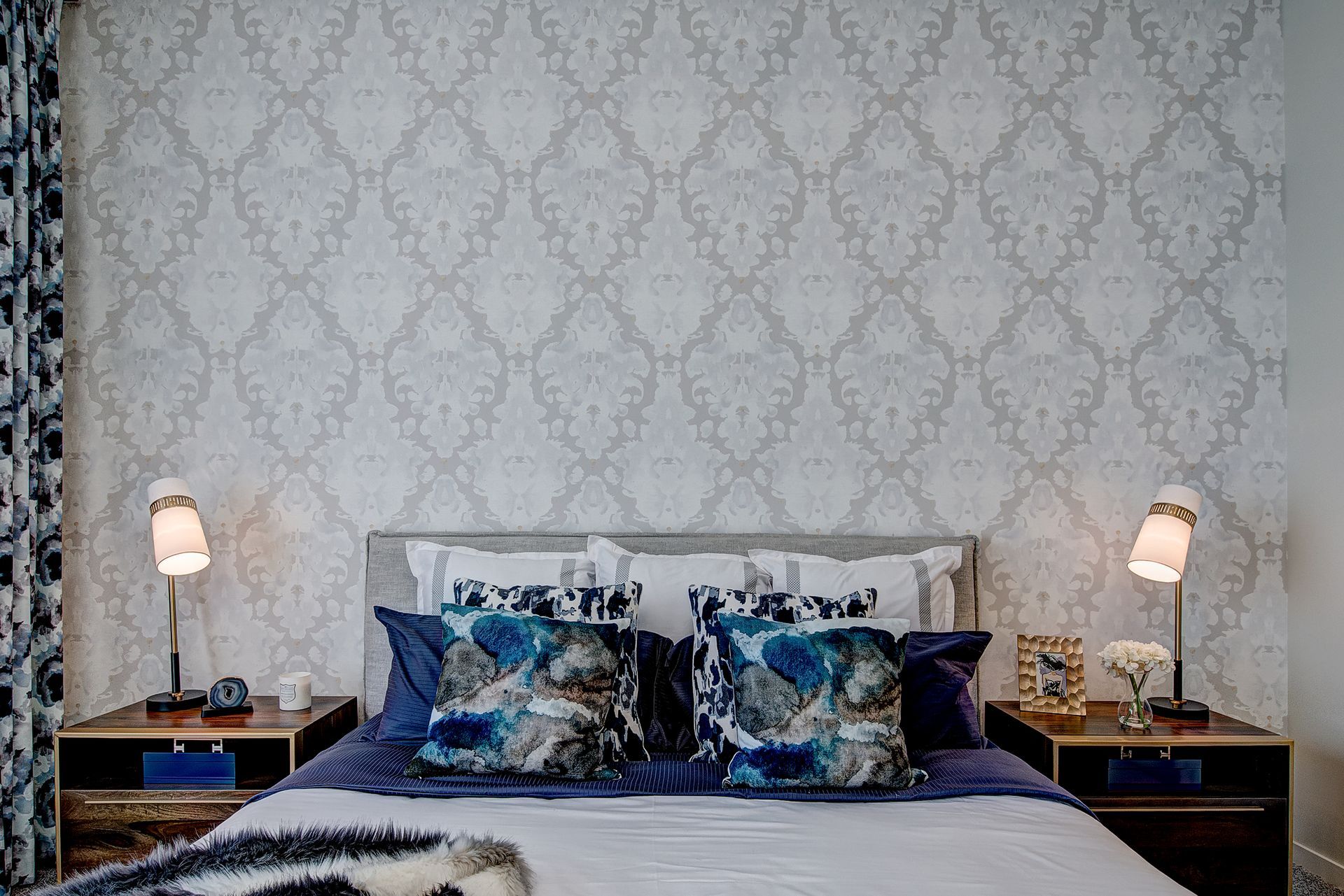 A bedroom with a bed , nightstands , and lamps.