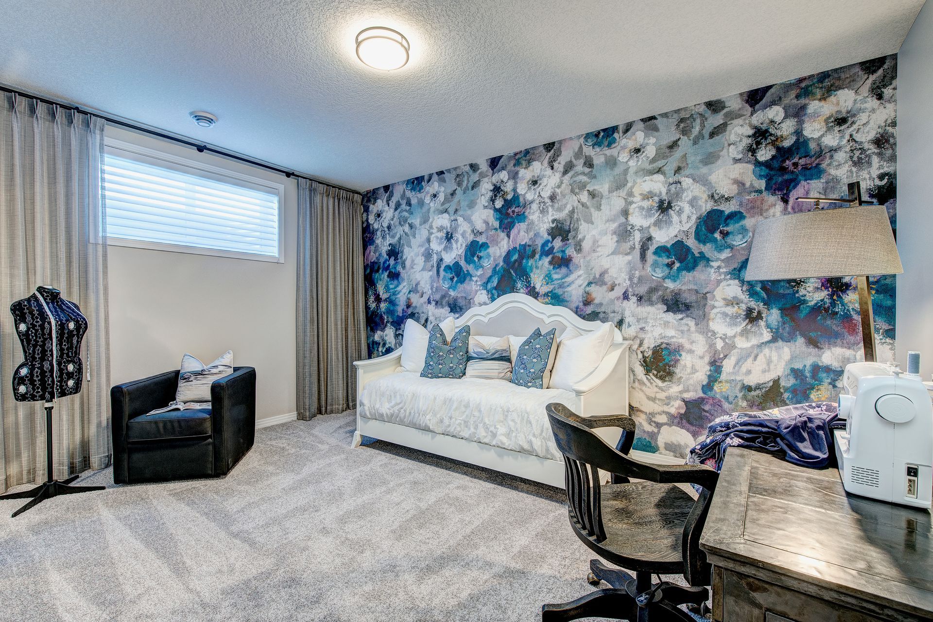 A room with a couch , chair , desk and sewing machine.