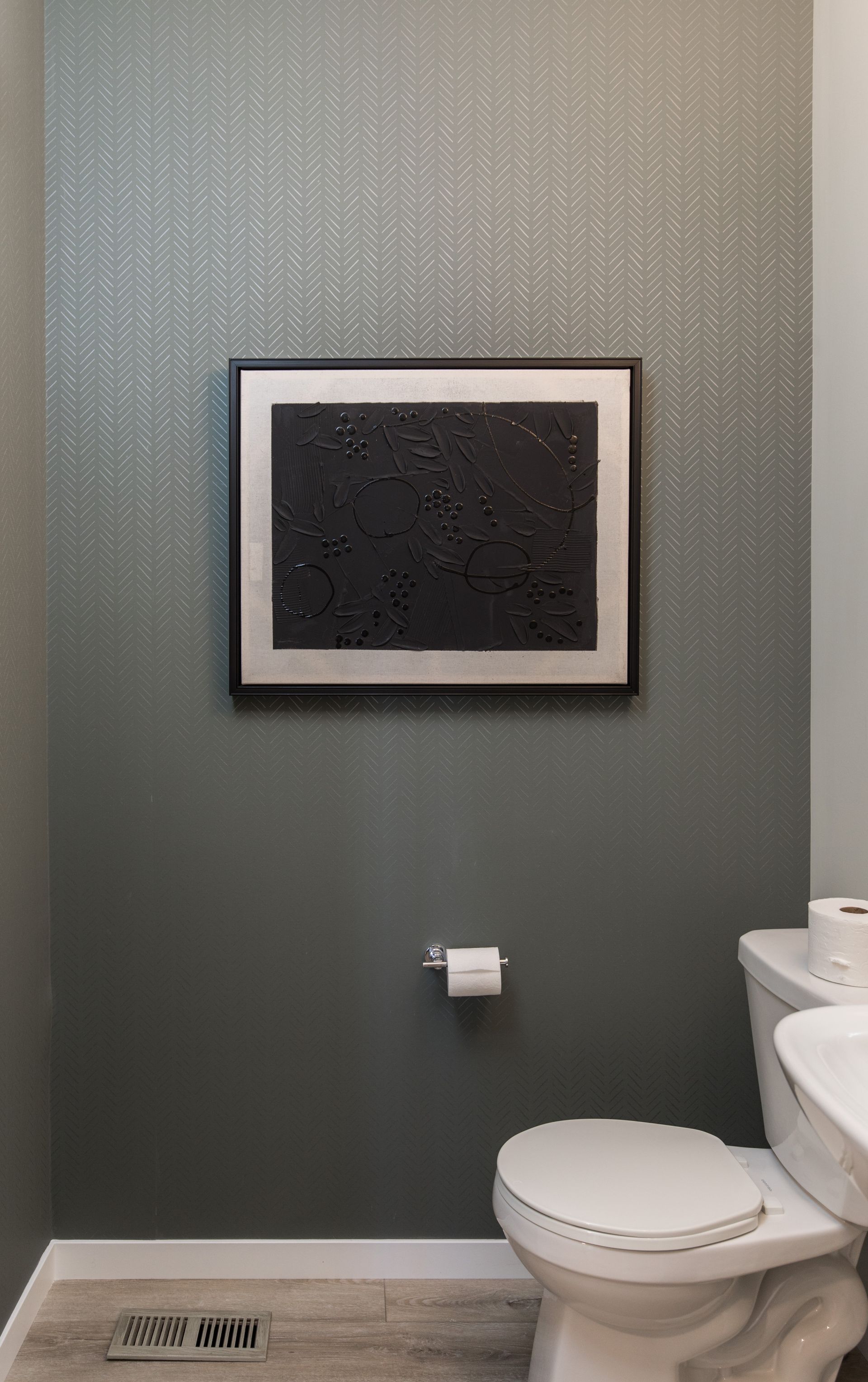 A bathroom with a toilet , sink , and picture on the wall.
