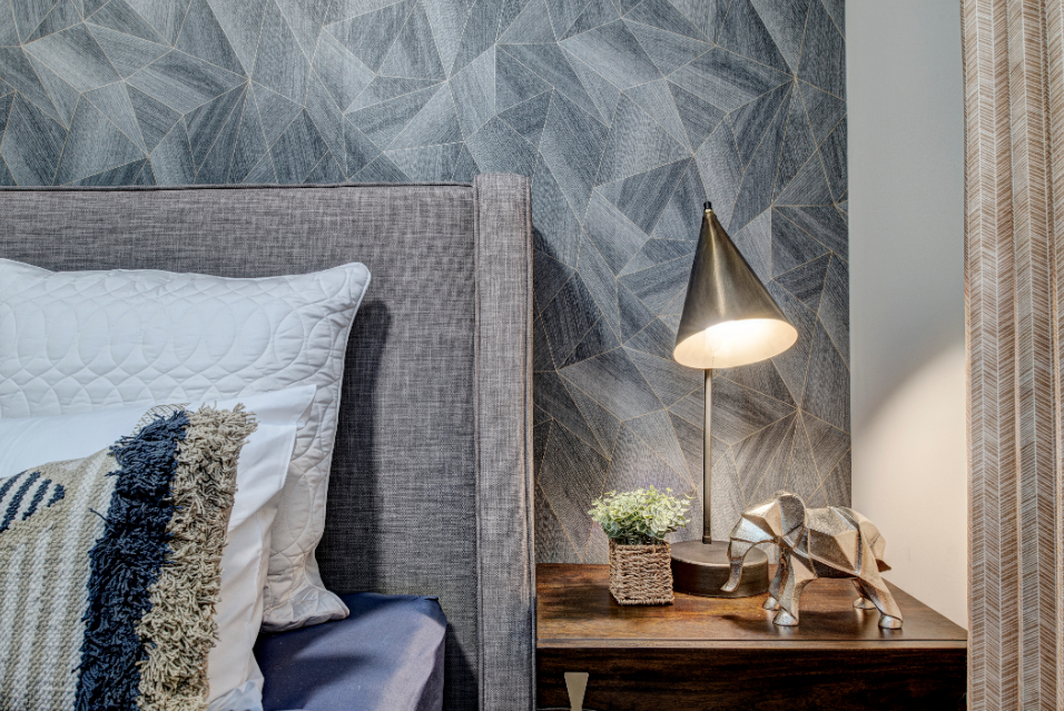 A bedroom with a bed , nightstand , lamp and elephant statue.