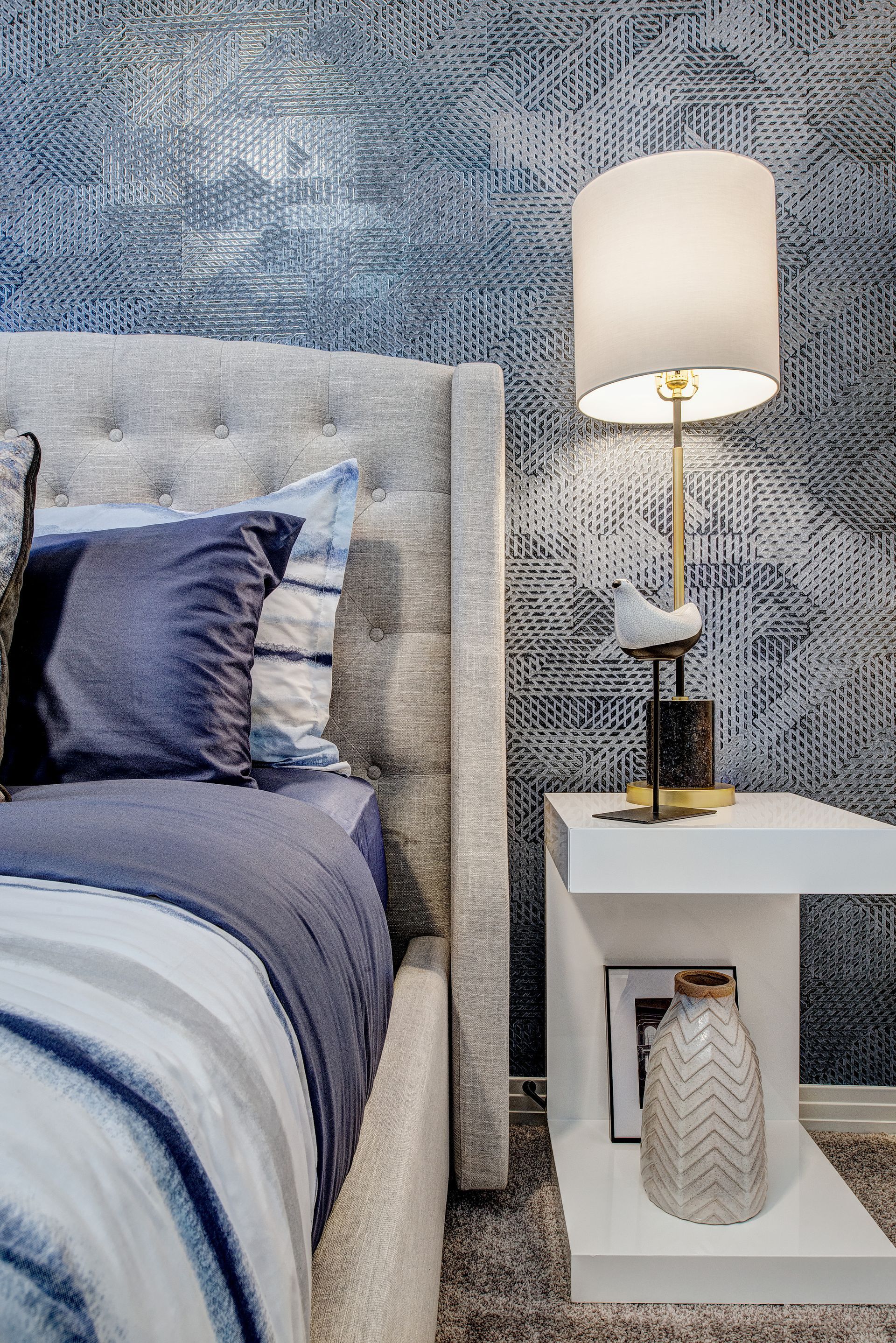 A bedroom with a bed , nightstand and lamp.