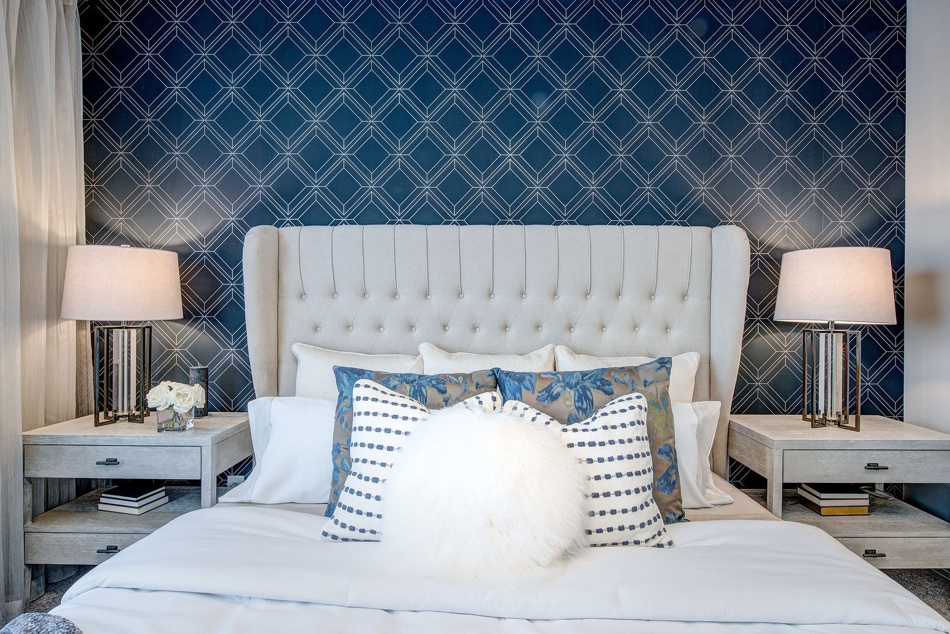 A bedroom with a bed , nightstands , lamps and a blue wall.